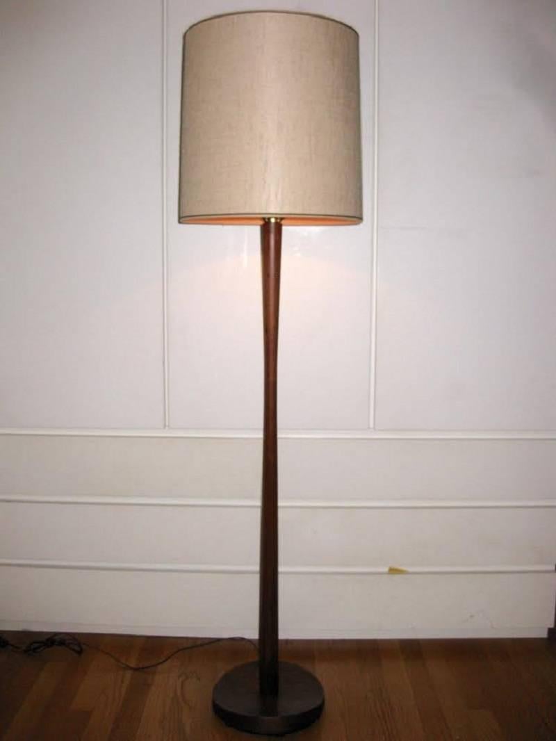 Beautiful Mid-Century Modern era, Danish teak wood floor lamp. The neck of the lamp has an elongated hourglass shape with a veneer over metal, and a curved top base. The base is reminiscent of old wooden hat forms. Comes with vintage shade. Heavy