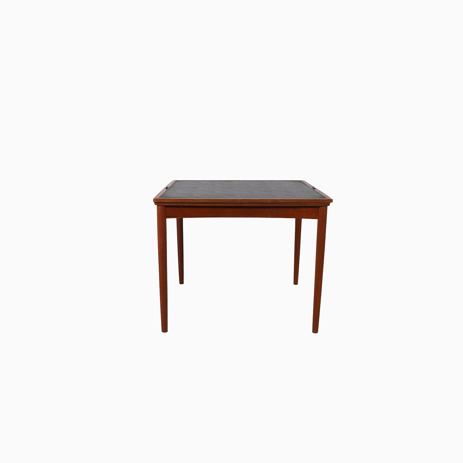 This is a danish modern dining table made from old growth teakwood that has a traditional oil finish.   It boasts a double sided 'flipping' top which has black vinyl on one side (think puzzles or cards) and an oiled teak surface on the other side