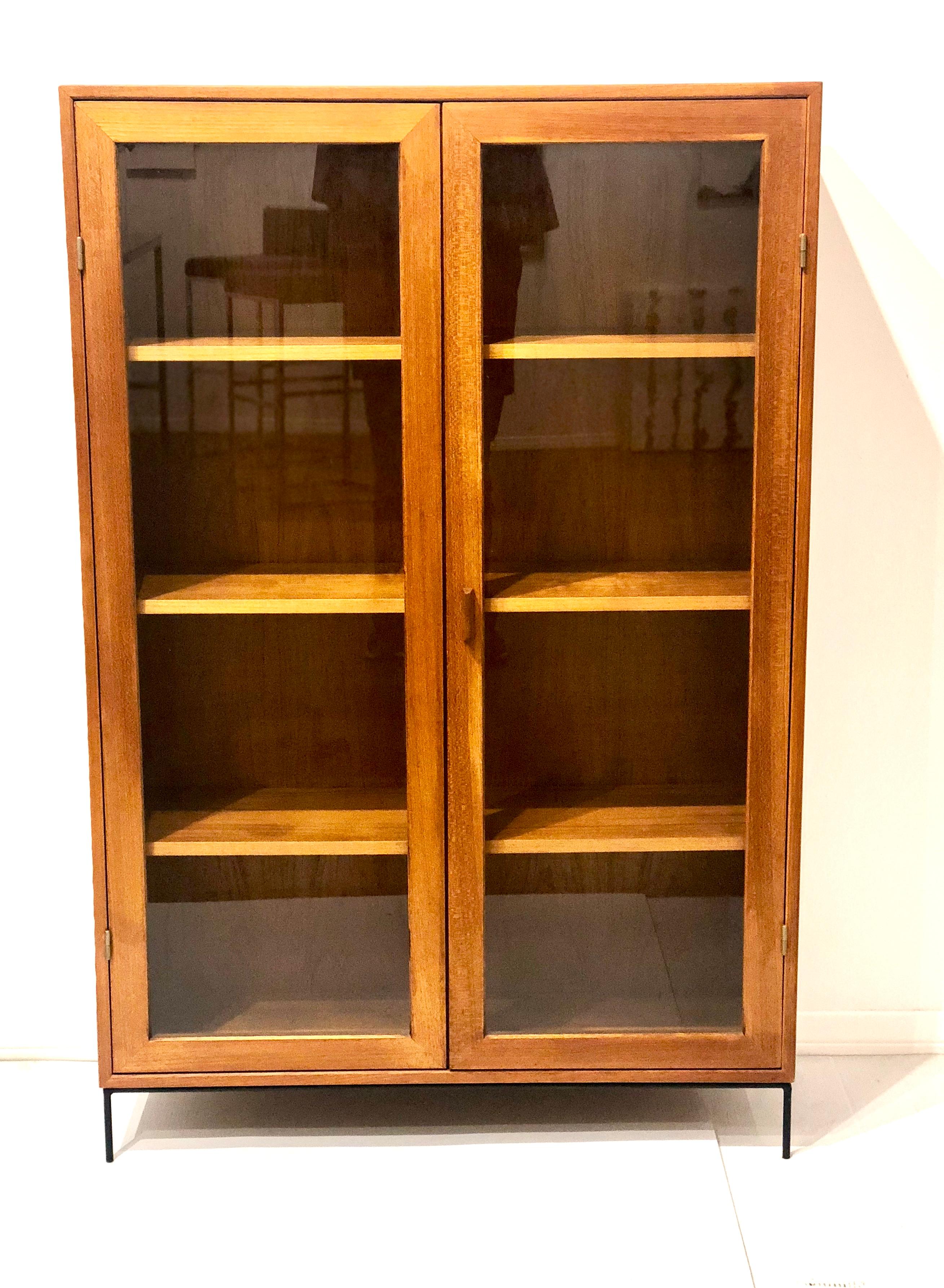Beautiful and versatile Danish modern teak bookcase with a bevelled wood edge front shelves with double glass doors, and removable shelves, sitting solid iron base. Great size and very rare to find. The case has been completely refinished and is in