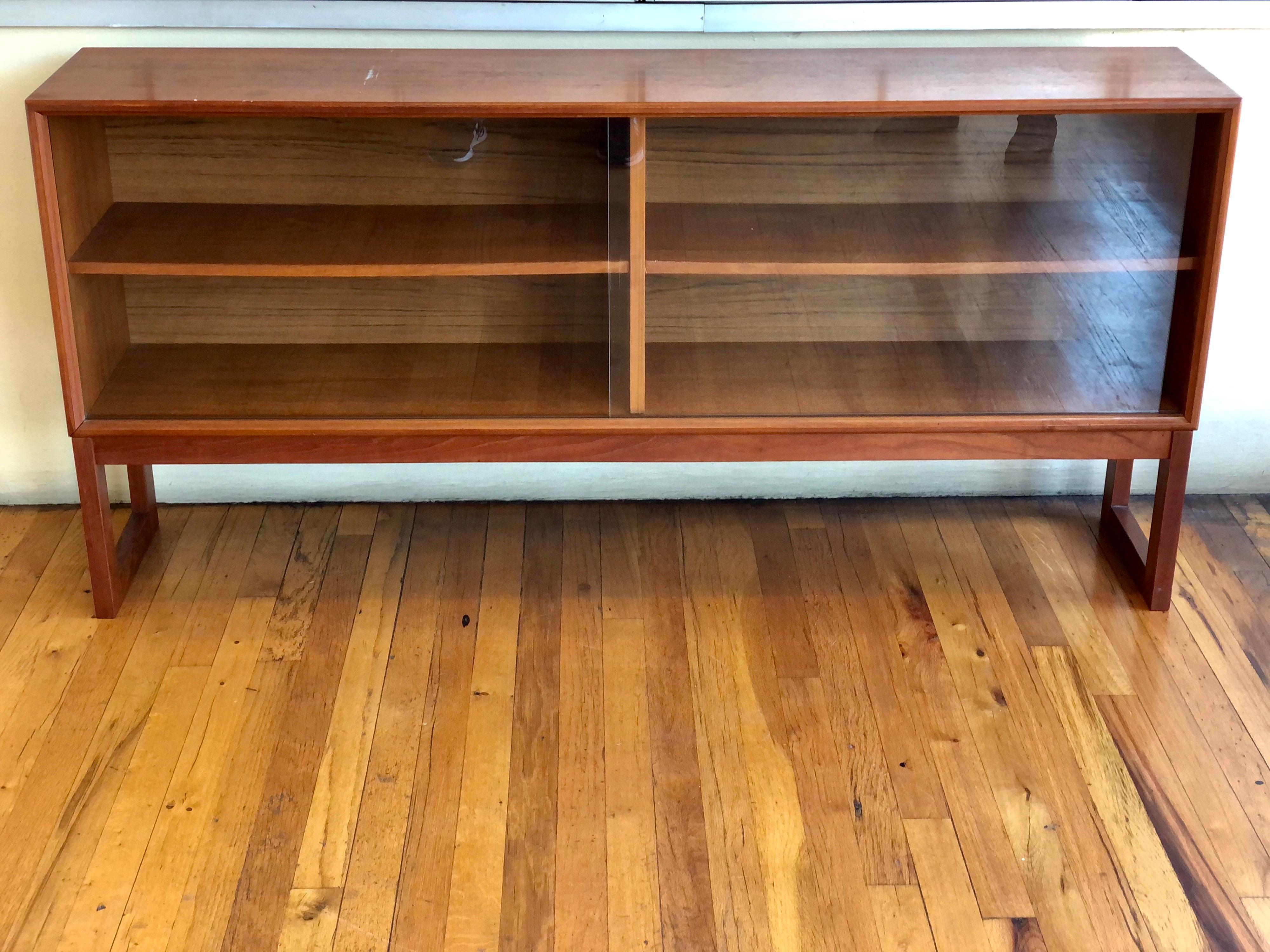 Versatile low cabinet bookcase in teak with glass sliding doors designed by Gunni Omann, for ACO Mobler Denmark, circa 1960's nice condition we have lightly sanded and oiled the piece looks great. With removable shelves.