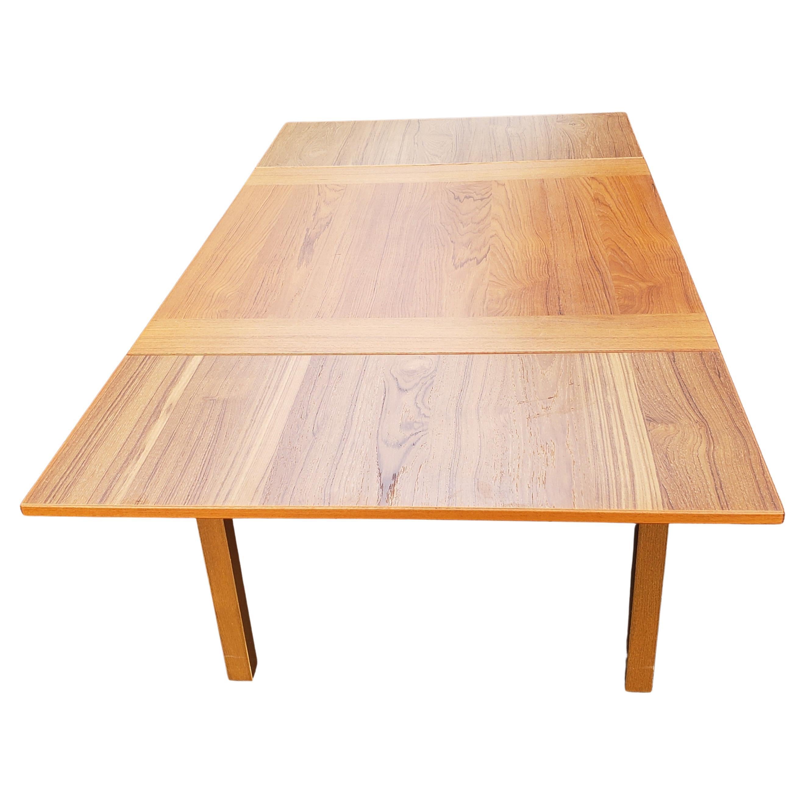 Elegant 21st century 100% teak dining table attributed to Gudme Møbelfabik in Denmark. 
This table is made out of teak wood and comes with tapered legs and two hidden pull out leaves that can be used to extend the table to 65.5