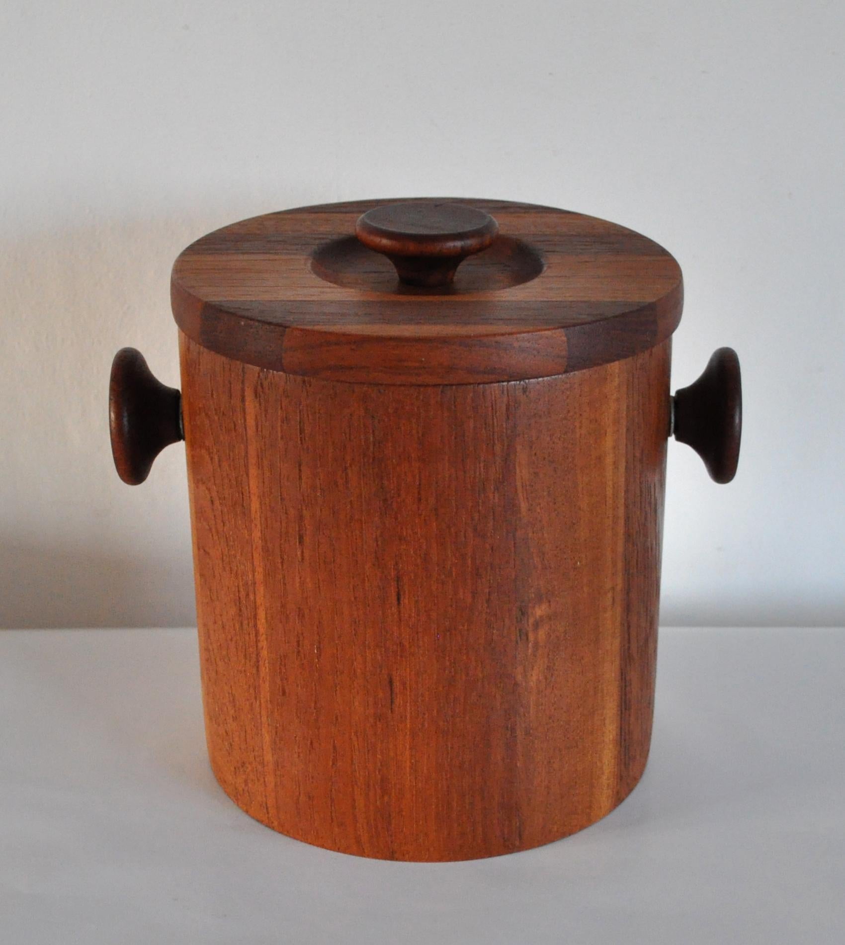 A beautiful cylindric ice bucket with lid from the 1960s-1970s. Designed by Lüthje Wood, Denmark. In fine condition with original white plastic liner, see picture 6. Includes original teak adorned ice tongs.
    
