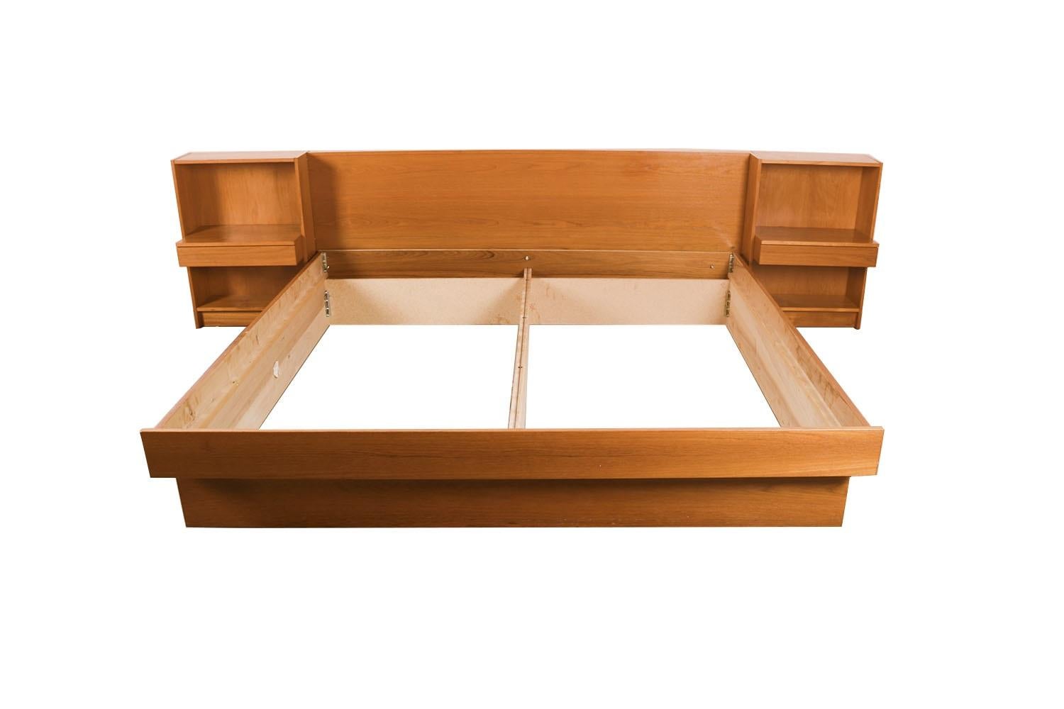 A remarkable Danish teak, mid-century King floating platform bed with nightstands, made in Denmark. Exceptional construction and style. Featuring a stunning headboard with attached nightstands, both with a wide surface area for placement of