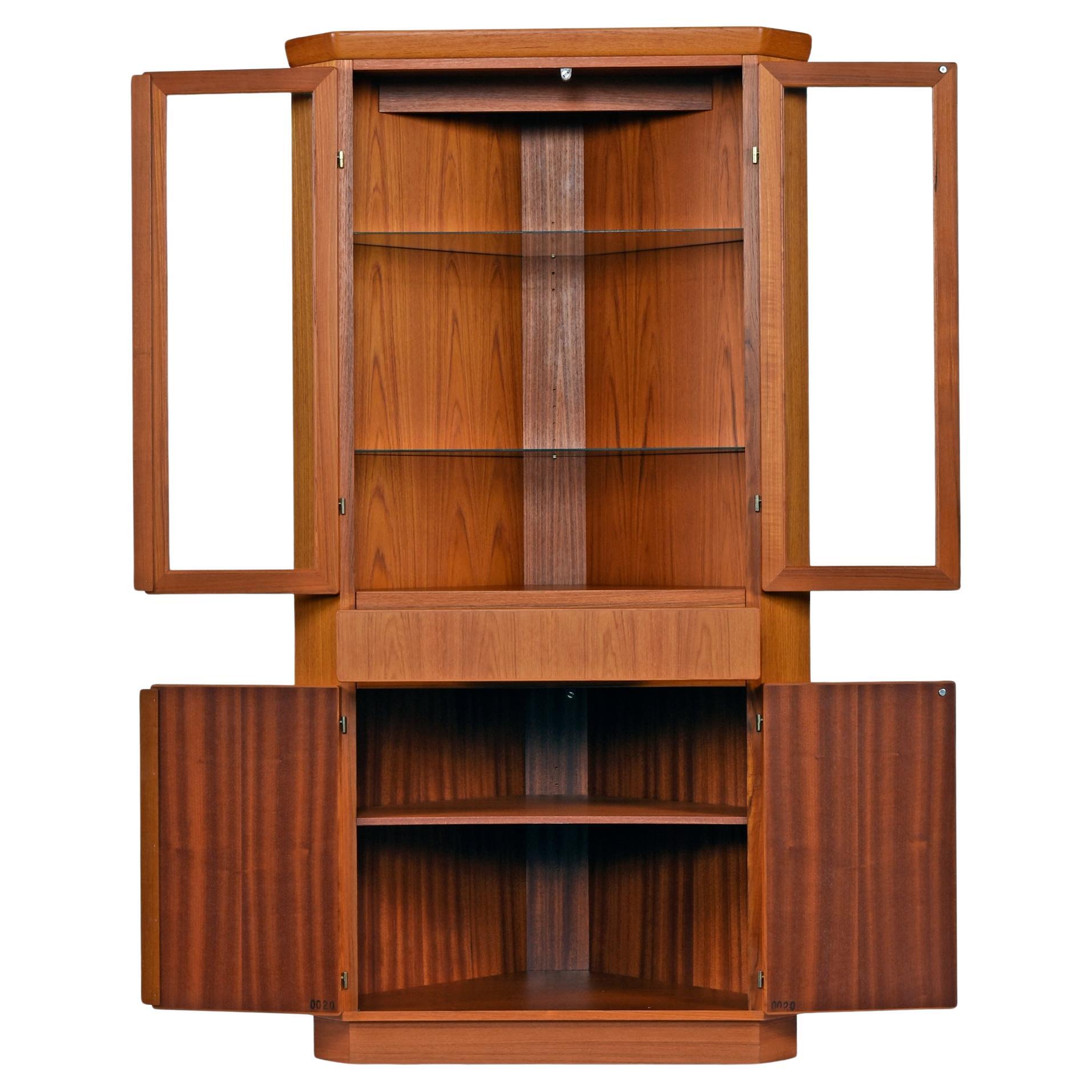 Vintage Danish teak corner display cabinet by Skovby. One piece unit with lighted display area on the top section. There are two glass shelves which are adjustable height and removable. A single light at top illuminates the display with a warm,