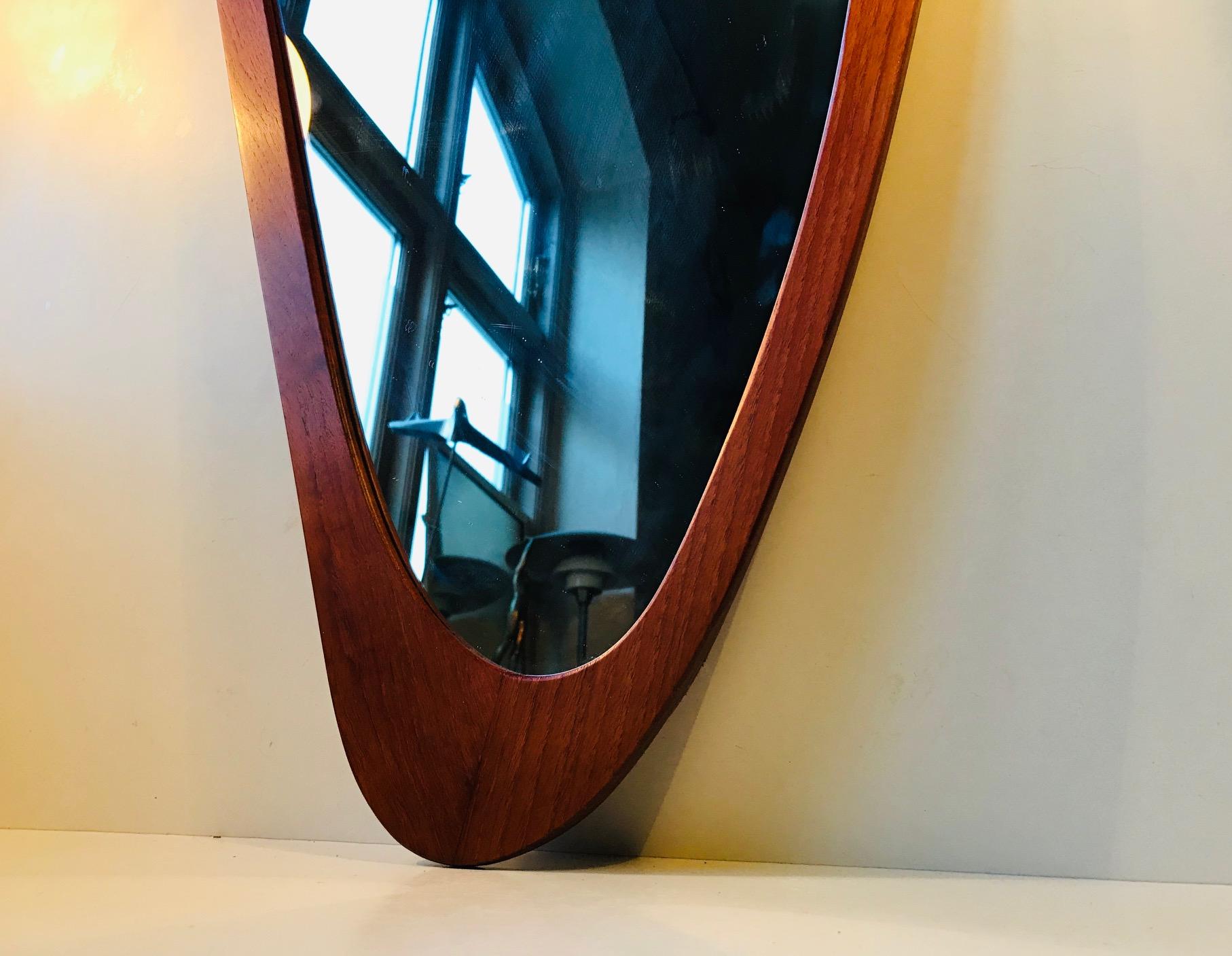 An organically shaped wall hung mirror with solid teak profiles that has been assembled without the use of metal. It was designed by Danish architect Rimbert Sandholdt and manufactured by M. J. Spejle in Denmark during the 1950s. It has remains of