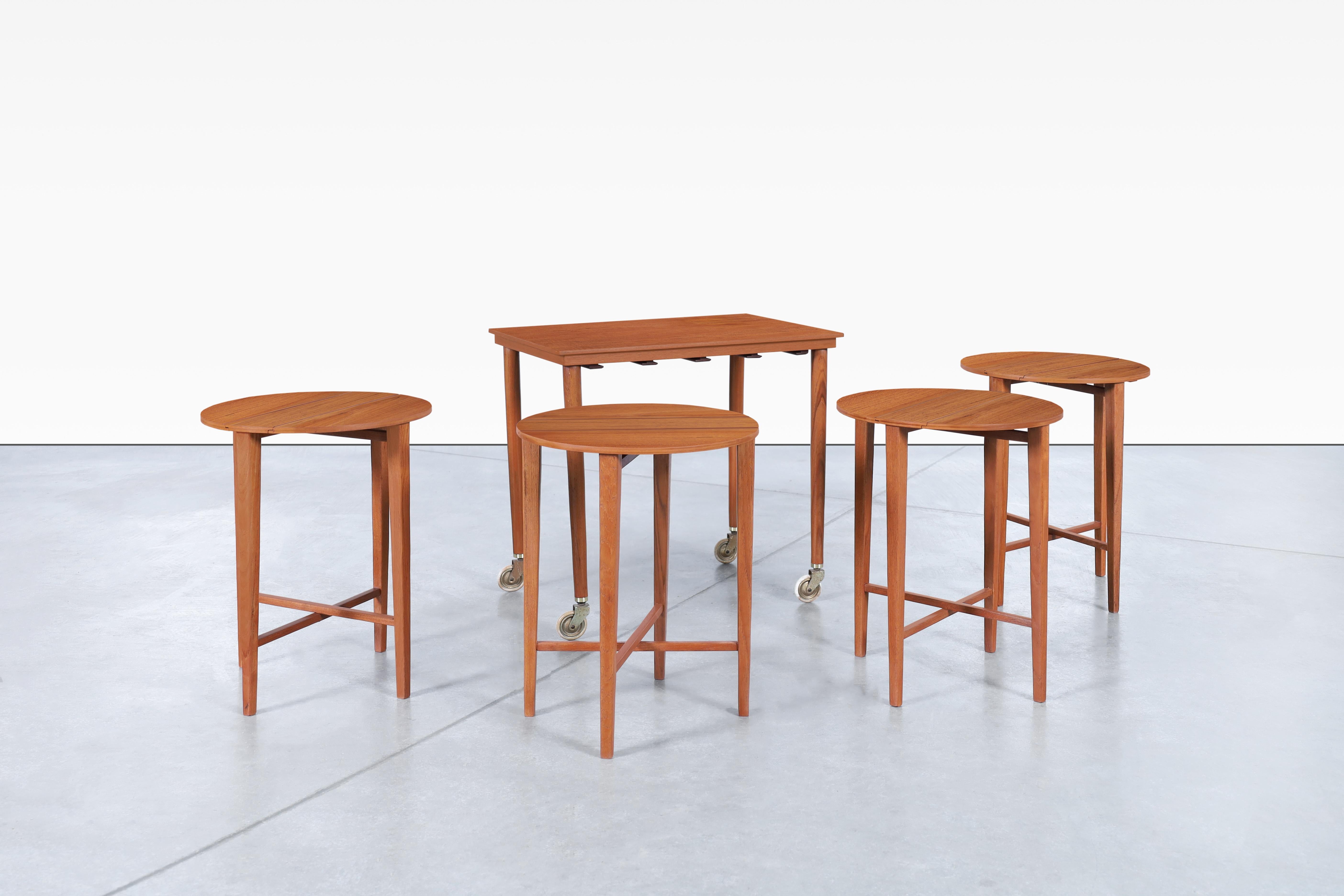 Beautiful Danish modern teak nesting table designed by Carlo Jensen for Poul Hundevad in Denmark, circa 1960s. Handcrafted with a teak top, beech legs and metal accents, this refinished piece is a testament to the art of thoughtful furniture. Four