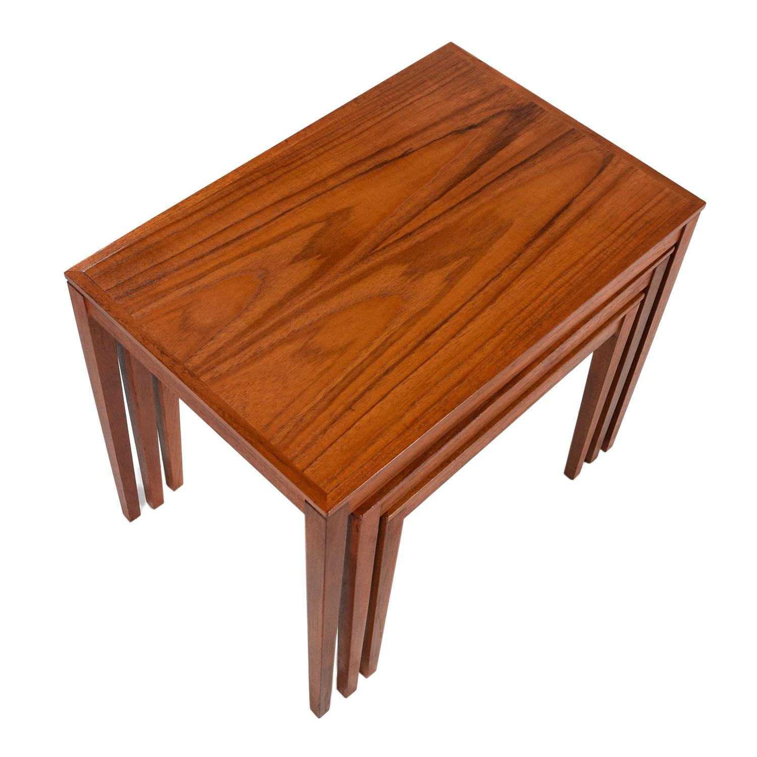 Set of three midcentury Scandinavian Modern Danish teak nesting tables of ascending size. Fine construction, solid teak bolt-on legs and old growth, fiery, cathedral grain are just a few notable qualities. Seamless joinery and classic Danish design