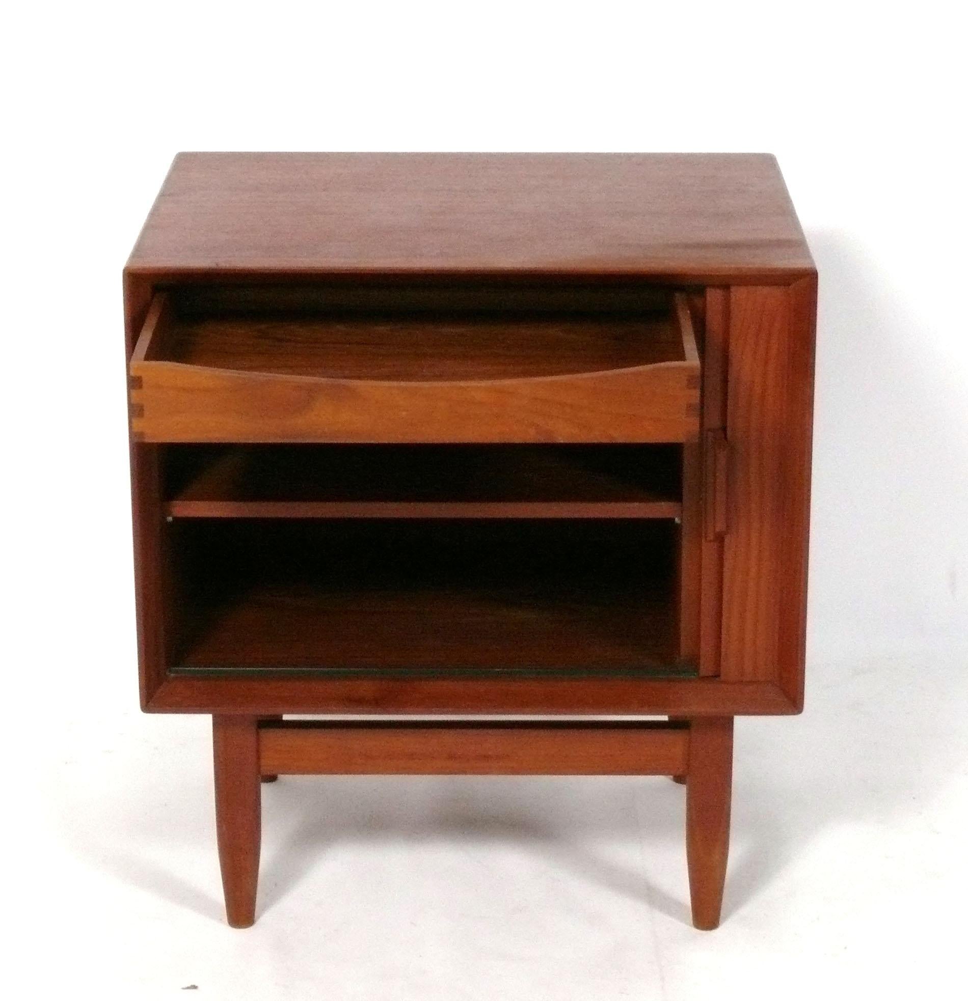 Dänischer moderner Nachttisch aus Teakholz, hergestellt von Falster Mobelfabrik, Dänemark, ca. 1960er Jahre. Er verfügt über eine Schiebetür mit Rollladen, die sich öffnen lässt, um eine Schublade und ein großes Staufach mit Einlegeboden