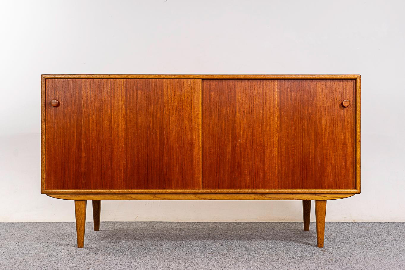 Teak & oak Danish sideboard, circa 1960's. Sleek lines in beautiful teak with contrasting solid oak trim and legs. Height adjustable shelving and removable legs.

Unrestored item with option to purchase in restored condition for an additional $300