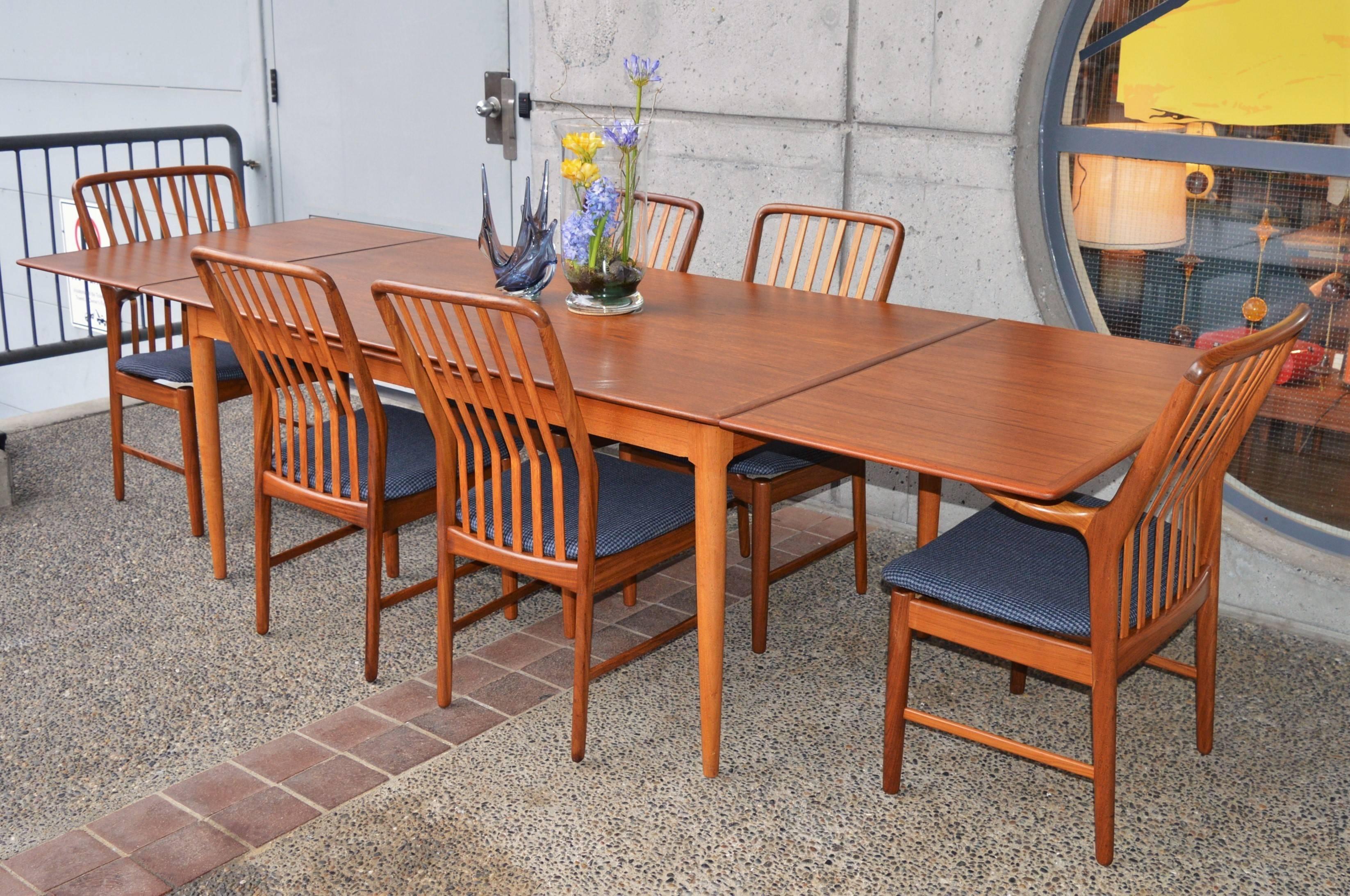 This awesome Danish modern teak draw leaf dining table is a much larger size that typical, with three chairs able to fit between the legs. It has two leaves that store under the tabletop and can be drawn from the ends as needed. With the leaves