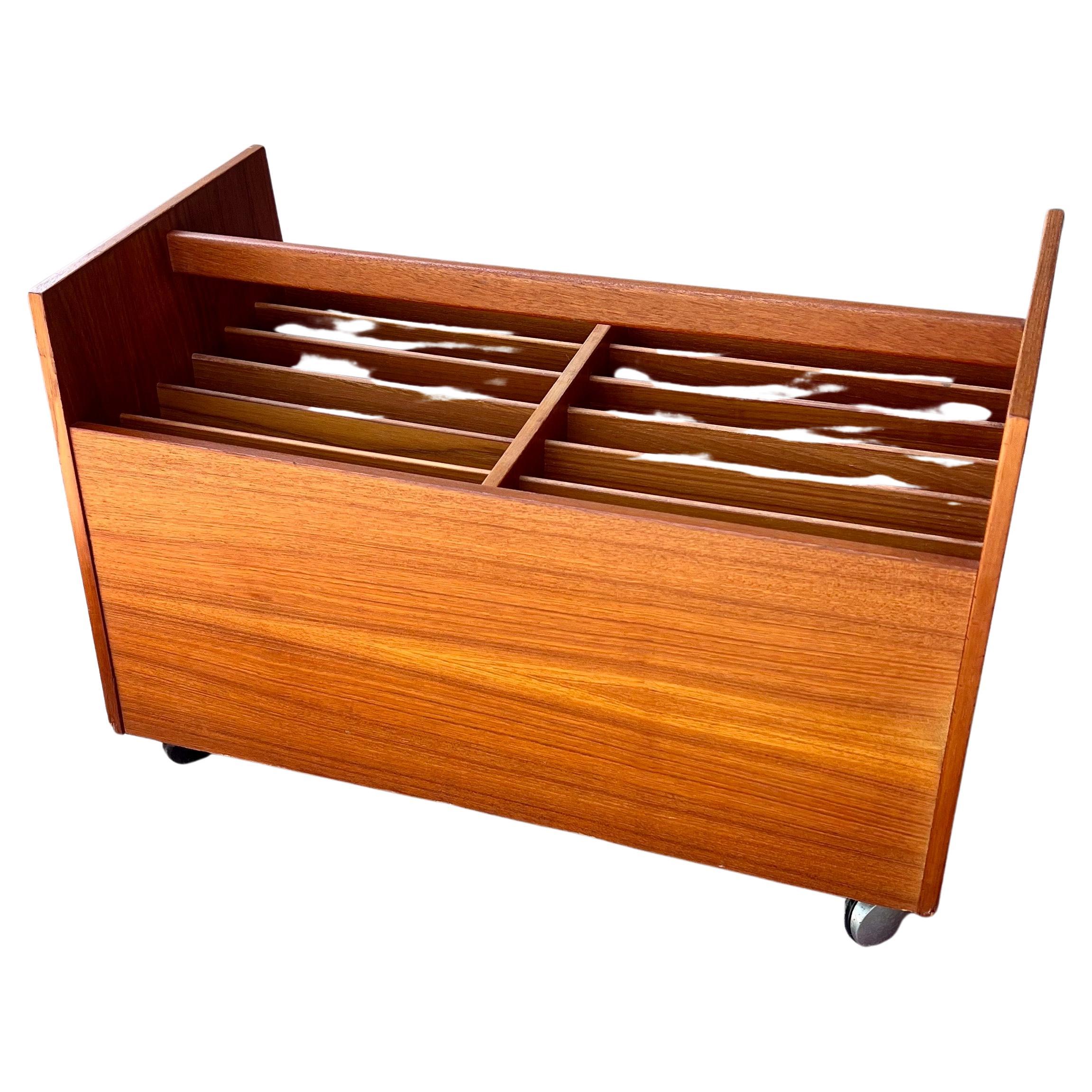 This magazine rack or record cart highlighting the beautiful natural grain of teak wood was made in Norway by the wood crafting company Mellemstrands. The piece, which features lots of storage compartments and rests on four chrome casters, is marked