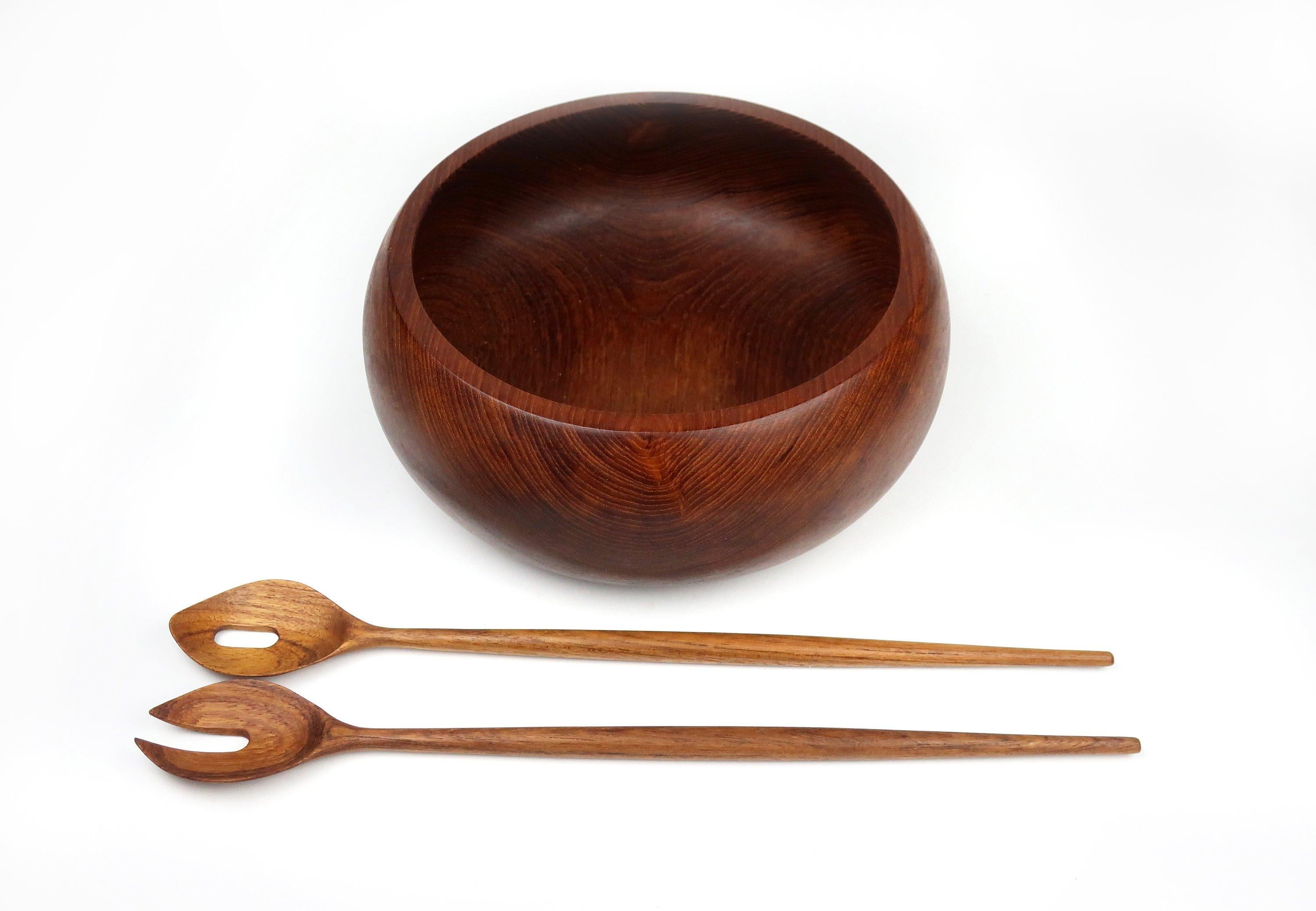 A lovely teak salad bowl and serving utensils. The weighty wooden bowl features Classic Danish Modern design touches and the sleek utensils provide a perfect accompaniment. 

Bowl is marked on the underside (made by Action Industries) but the