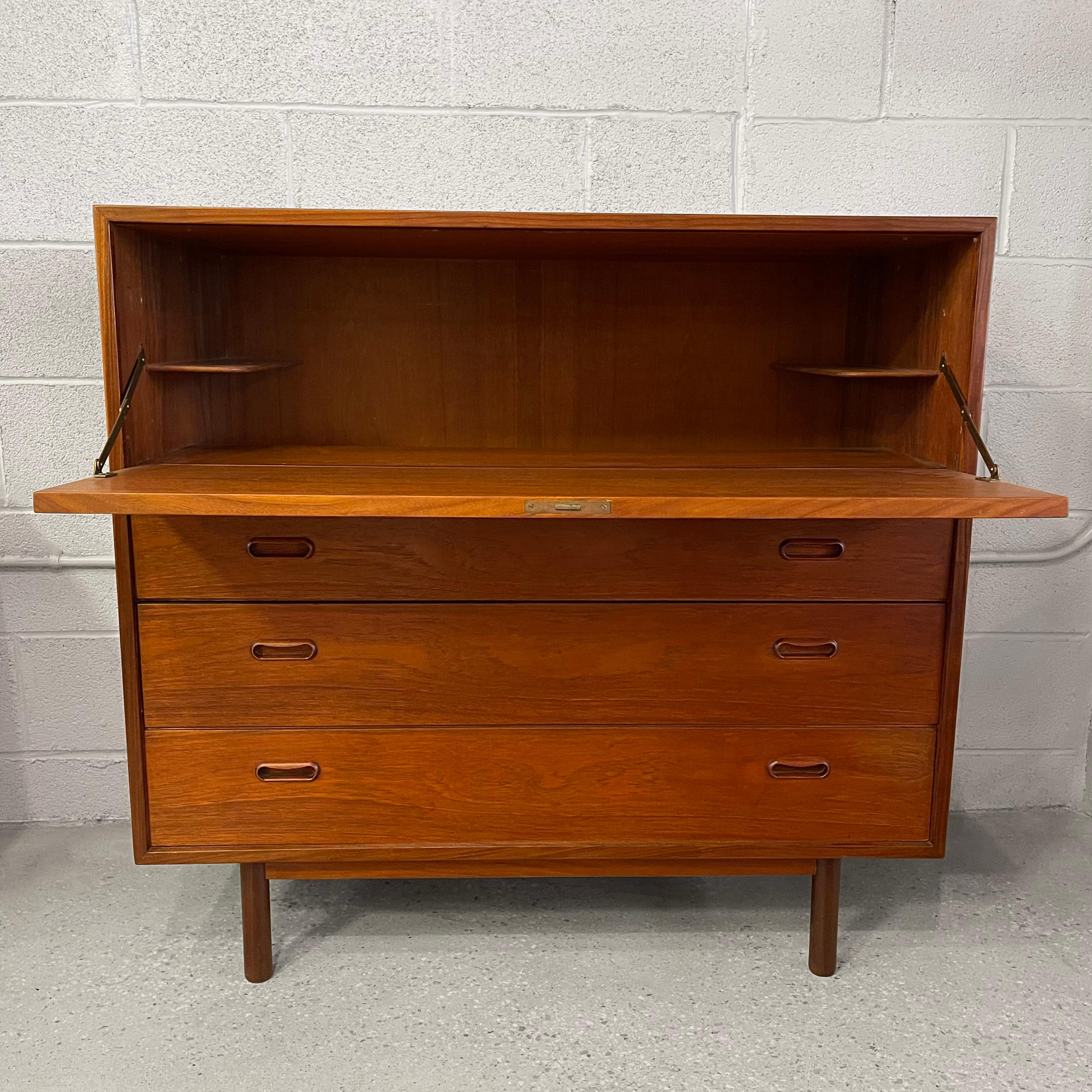 Danish modern, teak, secretary desk cabinet features a lockable, pull-down desk ledge at 26 inches height with 2 drawers and a flap level right below the desk to slide in files or books. The desk offers a comforatable amount of work space that can