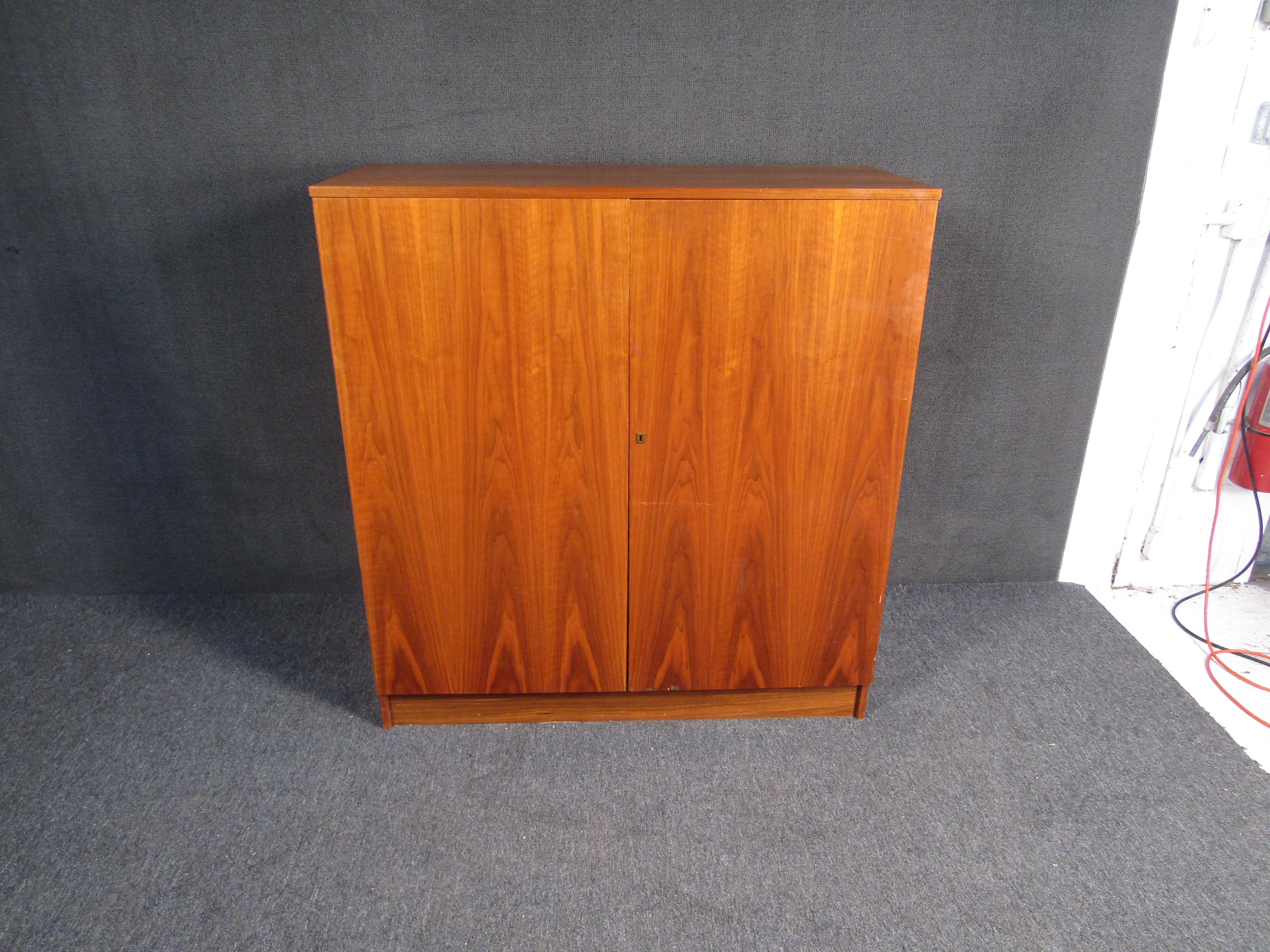 Rare and unique secretary desk finished in Teak. This Danish modern style secretary desk features 1 drawer and multiple shelves to file away paperwork and desk accessories. When not in use the writing surface folds up, and still allows access to the