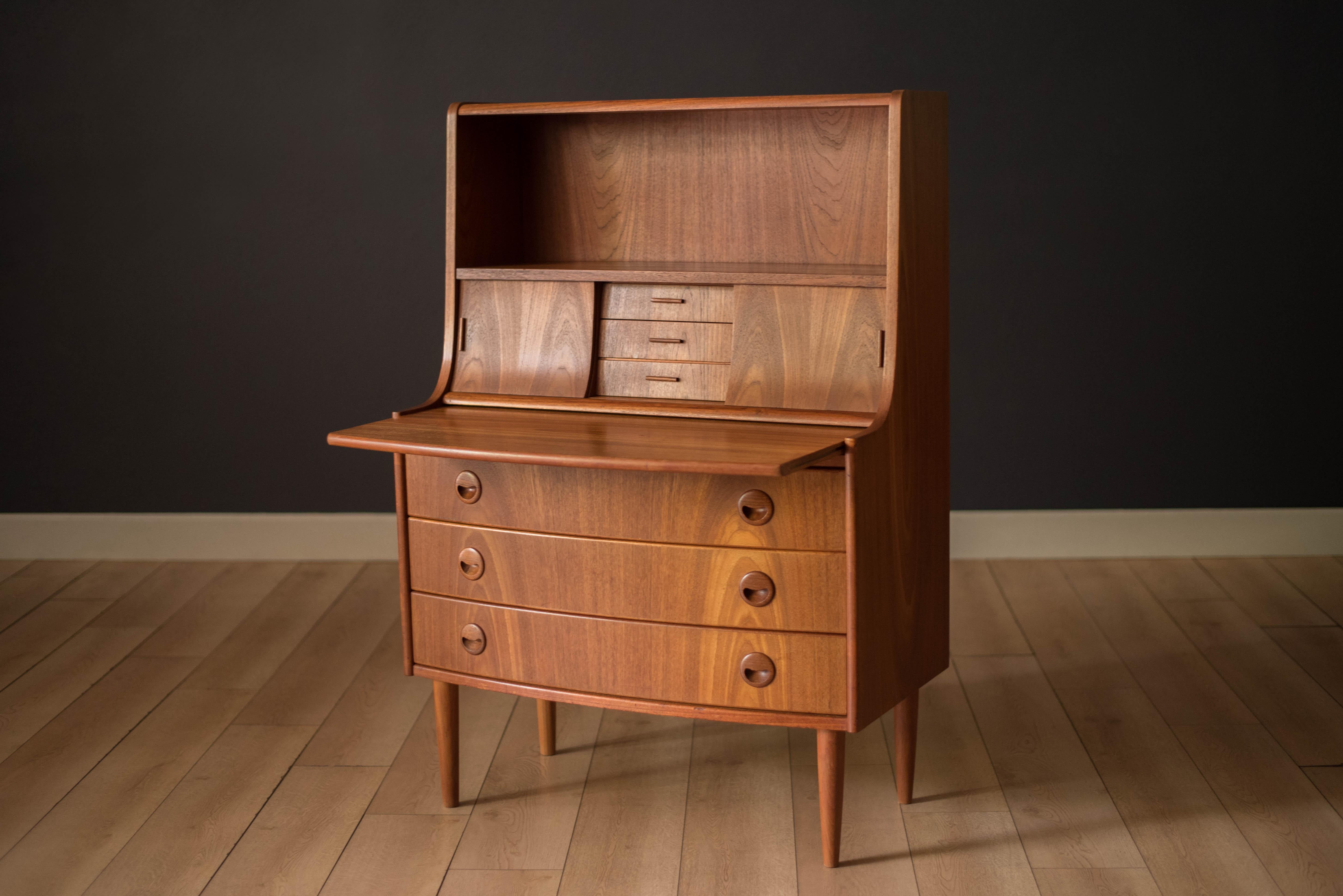 Mid-Century Modern secretary desk in teak circa 1960s, Denmark. Equipped with three deep storage drawers accented with sculpted wood handles. Features a slide out work desktop and includes a hutch with open compartments plus three additional small