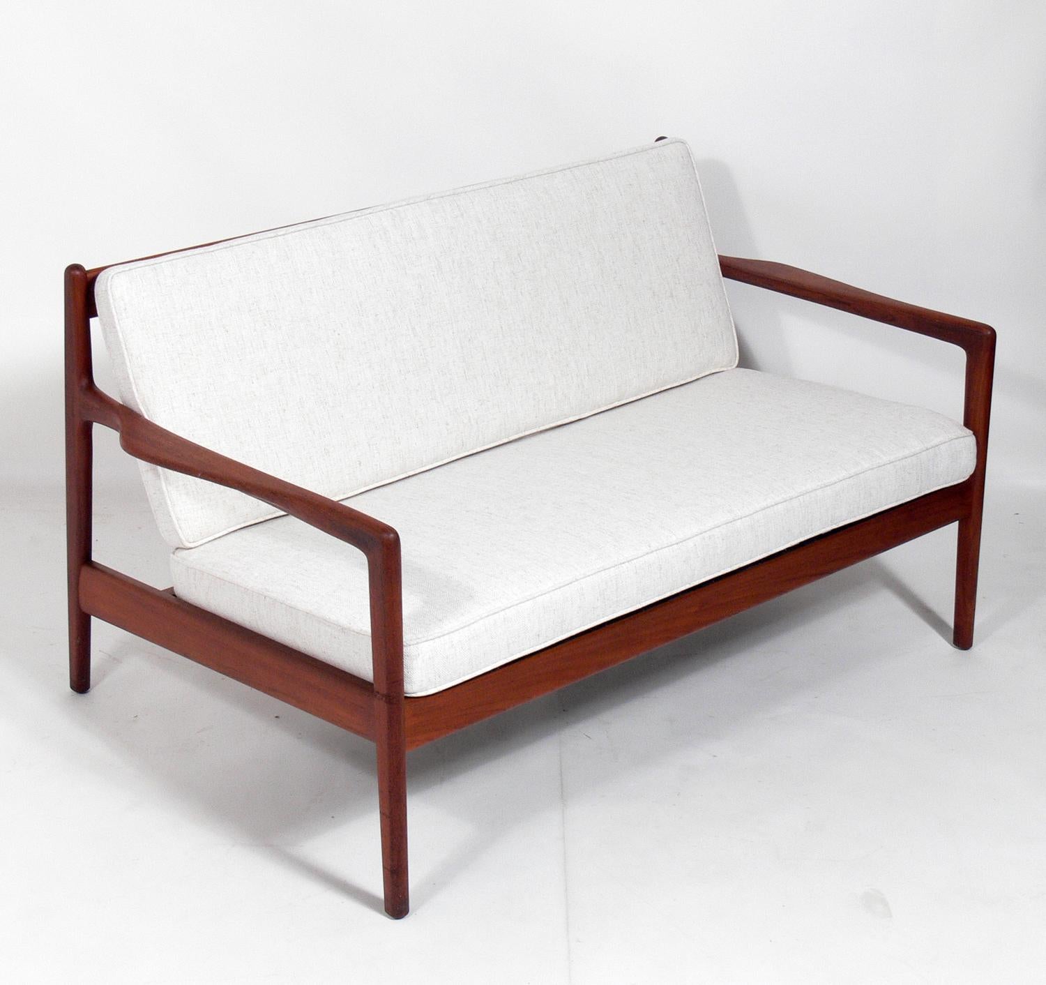 Danish modern teak settee or sofa, designed by Folke Ohlsson for DUX, Sweden, circa 1960s. It has been reupholstered in an ivory color herringbone upholstery. Teak frame cleaned and Danish oiled.
