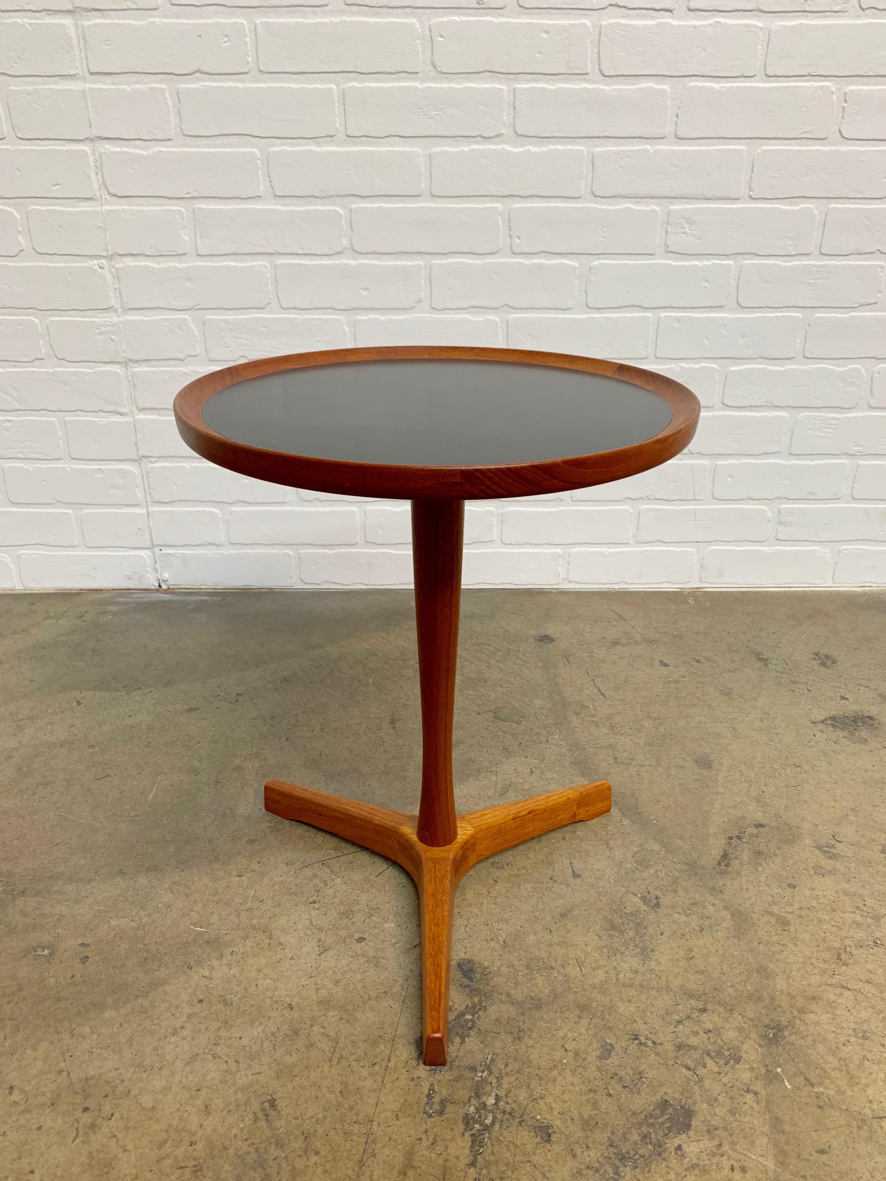Designed by Hans C. Andersen, Denmark. This drink table has a black laminate inlaid top and a solid teak pedestal base.