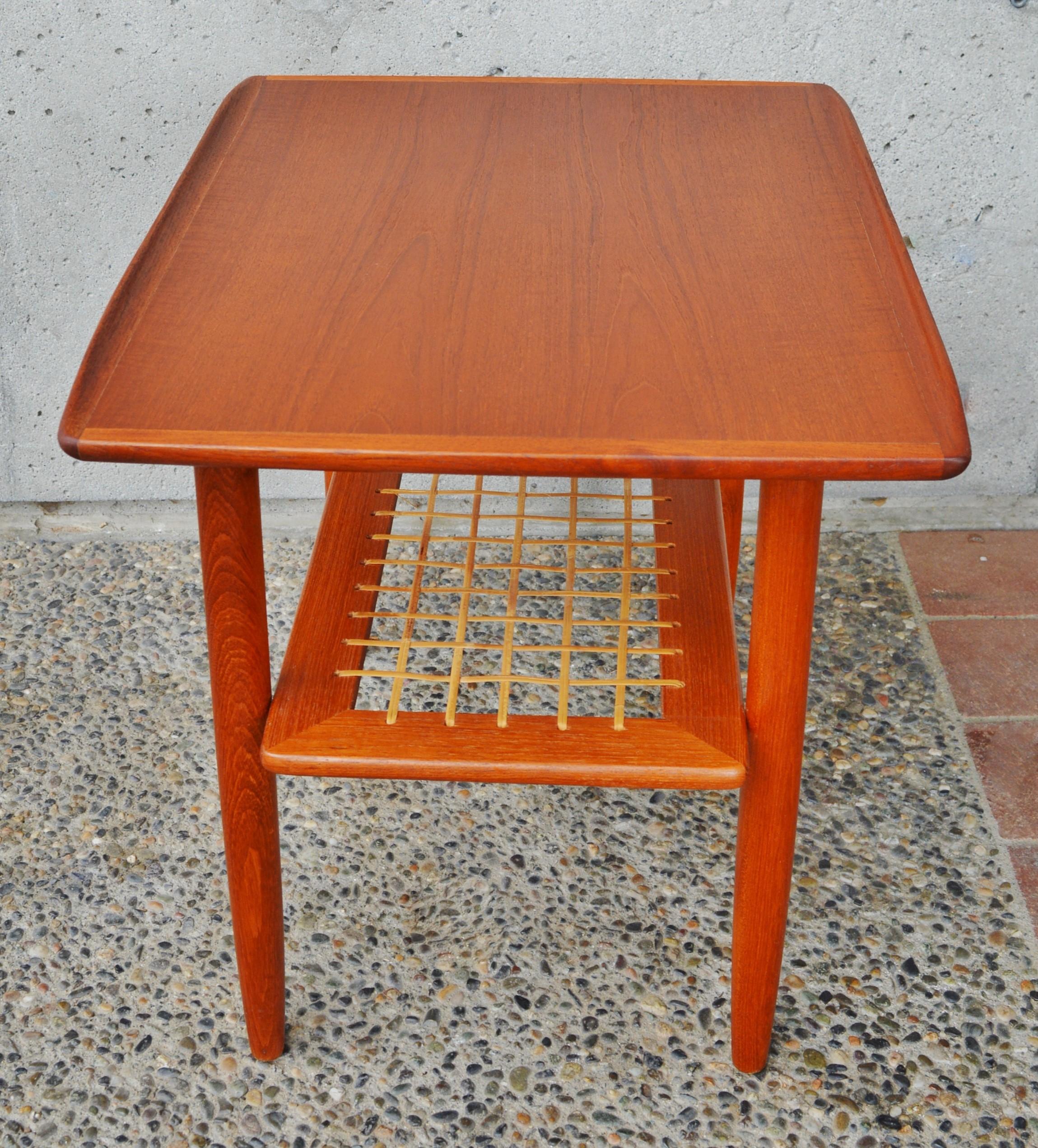 This sweet Danish modern teak side table has gorgeous styling throughout. Featuring flared top edges, classic conical legs, as well as a handy lower cane shelf. In fantastic condition and with a lovely patina. Disassembles for shipping.