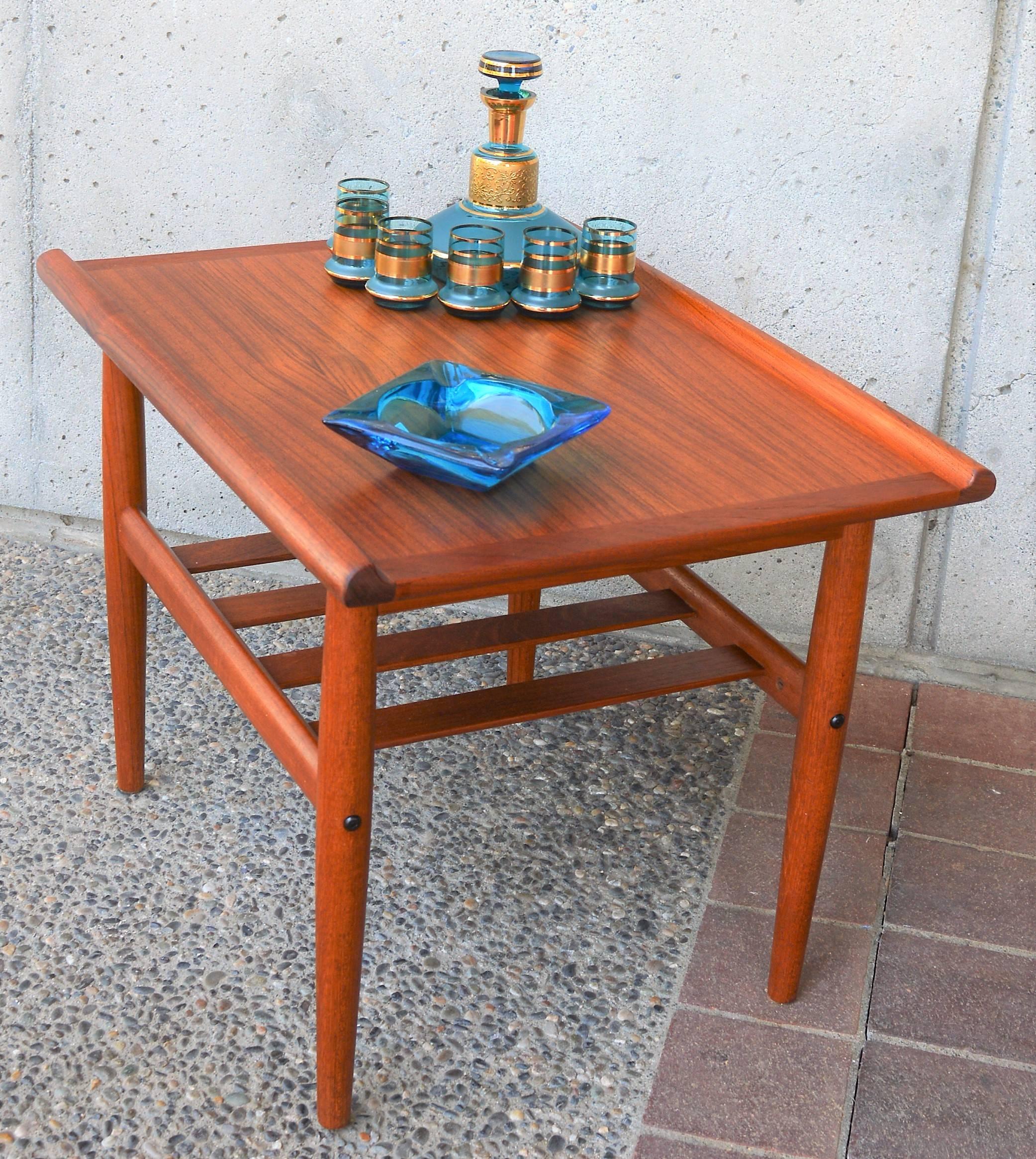This sweet Danish modern teak side table is in the style of Grete Jalk, with the sultry flared top edges, classic conical legs, beautiful grain and lower slat shelf. In gorgeous condition and freshly oiled.