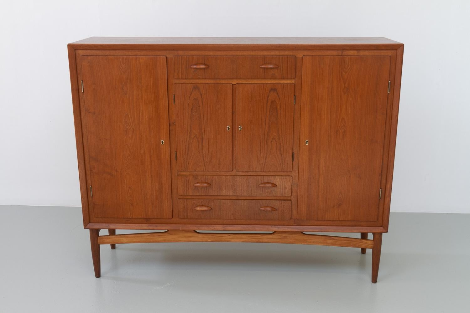 Danish Modern Teak Sideboard, 1950s.
Large Danish Mid-Century Modern sideboard in teak made in Denmark in the 1950s.
This credenza with slanted edge features three compartments with hinged doors behind which are adjustable shelves. All doors with