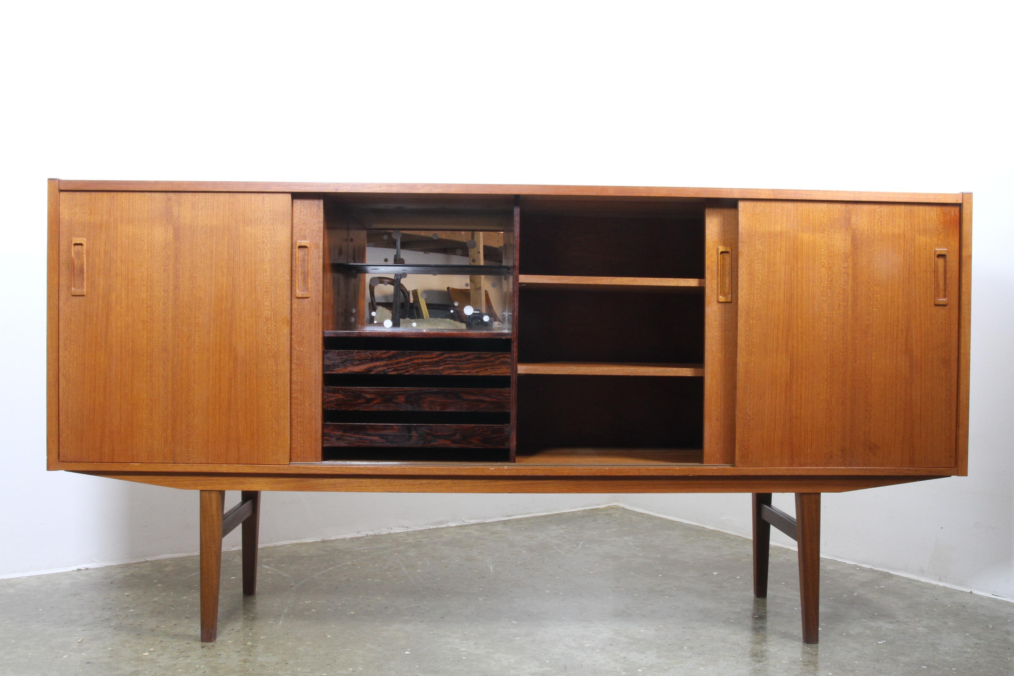 Beautiful Danish Mid-Century Modern sideboard with sliding doors. Behind the minimalistic front are shelves, drawers and a rosewood bar section with mirror.