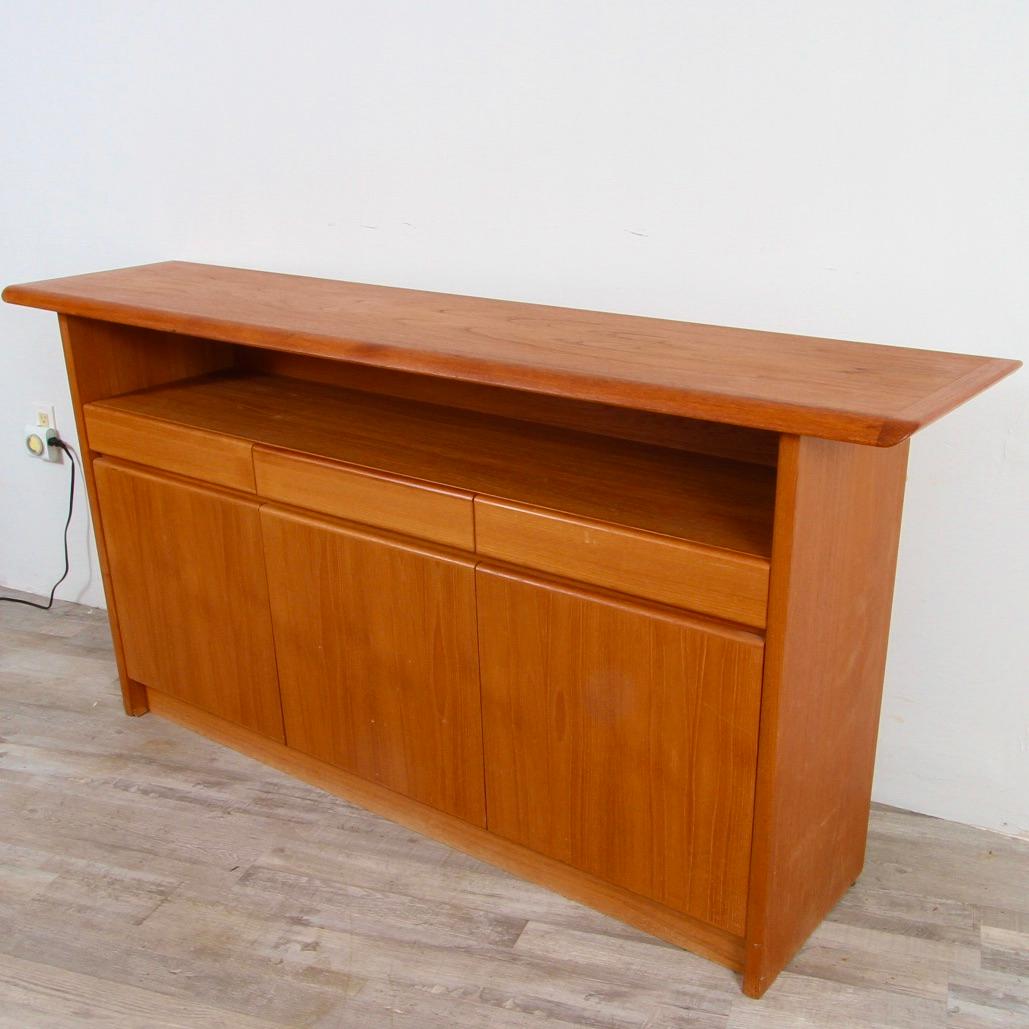 Later 21st Century Danish modern style teak server made by Nordic Furniture of Ontario Canada. Featuring a long shelf with three silverware drawers and 3 cabinets below.