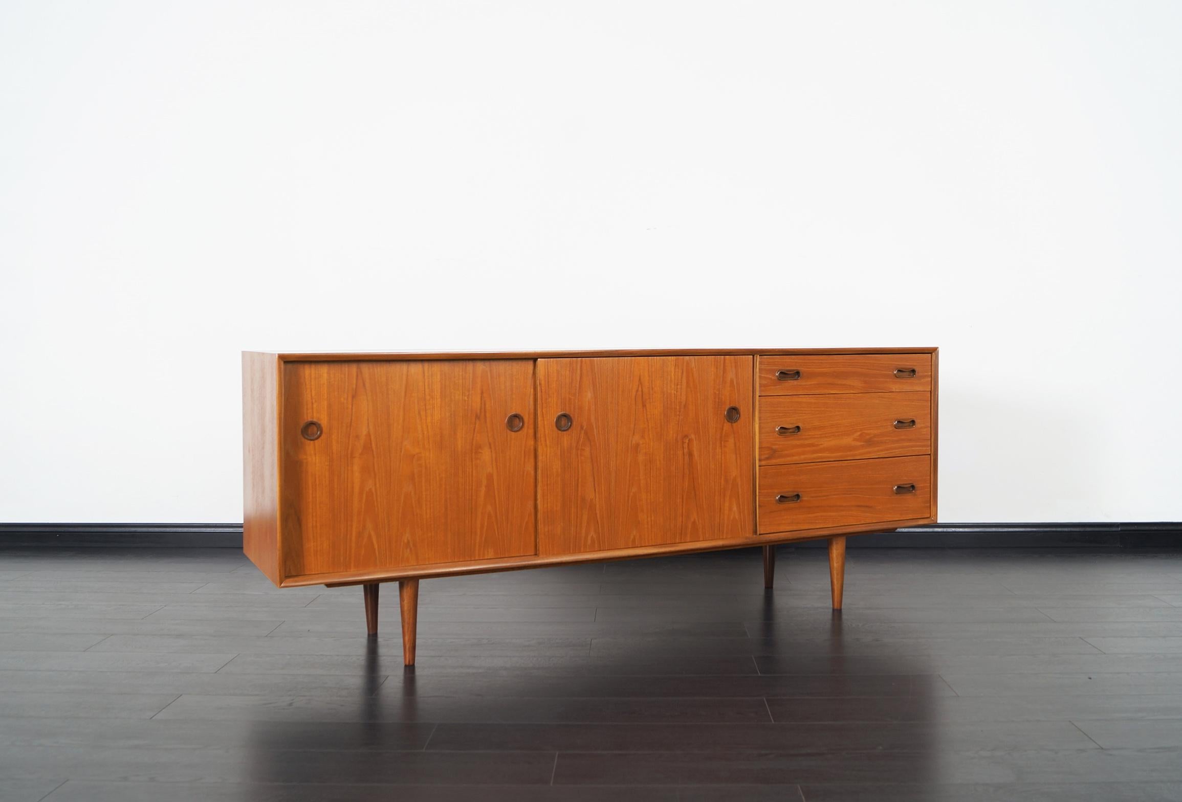 Danish modern teak sideboard features two sliding doors and three pullout / pull-out drawers.