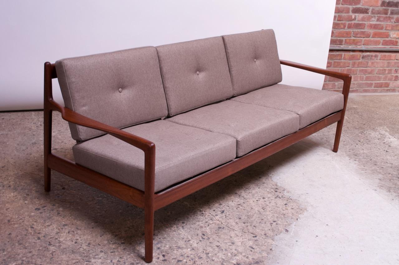 Danish Modern teak sofa attributed to Kofod Larsen for Selig. Composed of a slat-back construction and deeply sculpted armrests. Button tufted back and seat cushions. Newly reupholstered in a gray wool textile with new foam. The rubber webbing has