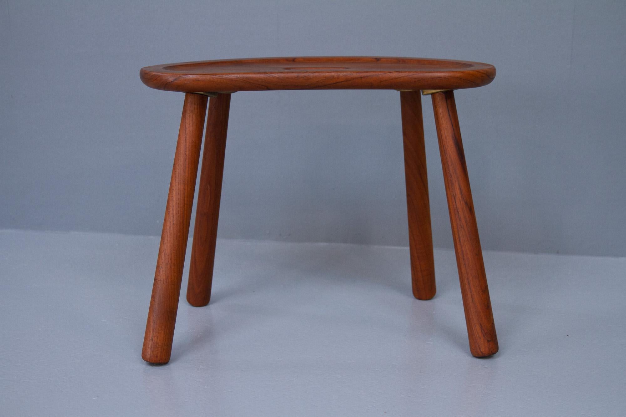 Danish Modern teak stool by ESA, 1950s.
Organically shaped Danish stool in solid teak. Beautifully sculpted seat. Four round legs with club shaped profile (like the Clam Chair), mounted with brass brackets. 
Very beautiful and simple yet