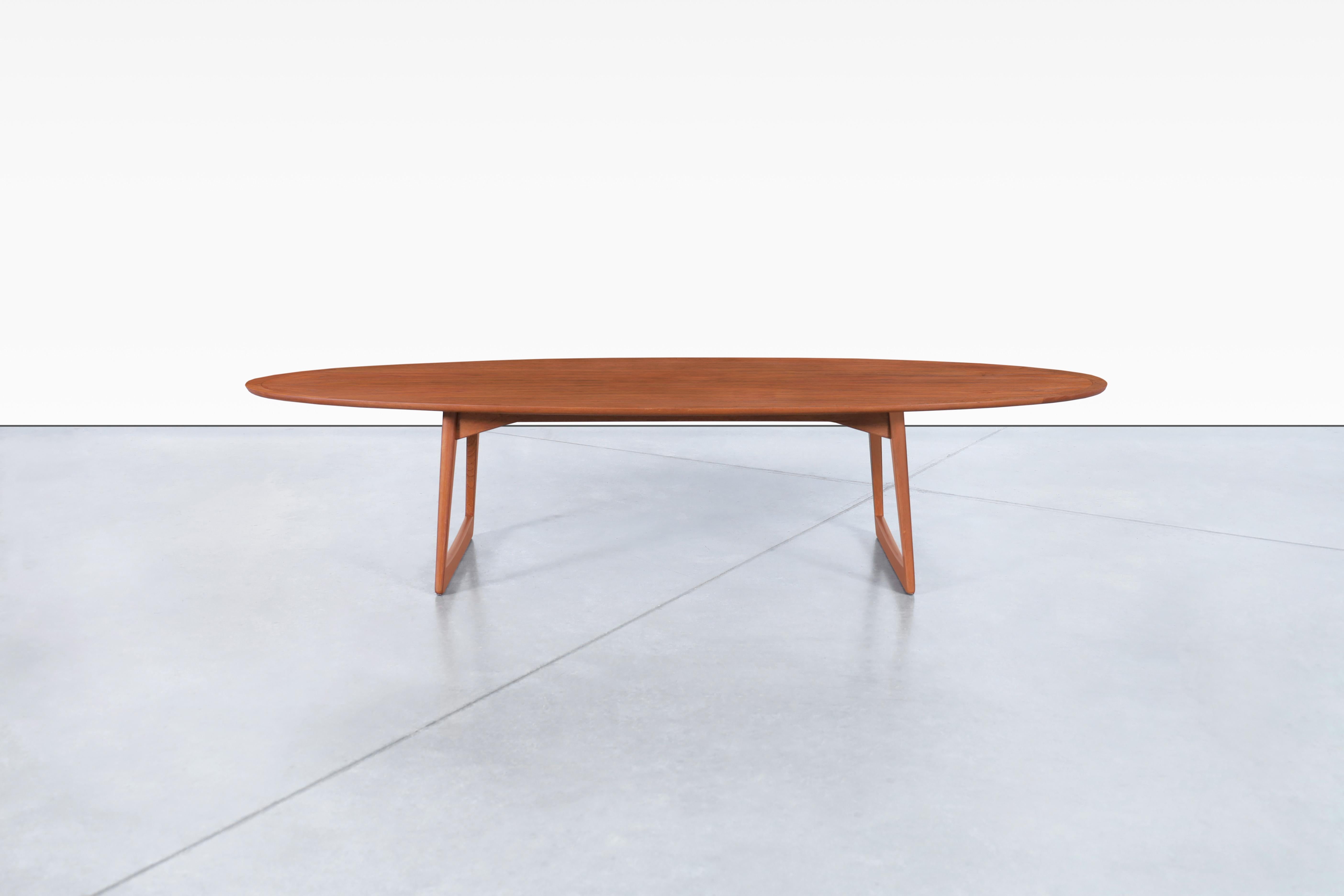 This elegant surfboard-style coffee table was imported from Denmark by Moreddi in the 1950s. Meticulously crafted from teak wood, it features a distinctive sled-style base with slightly angled sculptural legs. The tabletop showcases a rich, warm