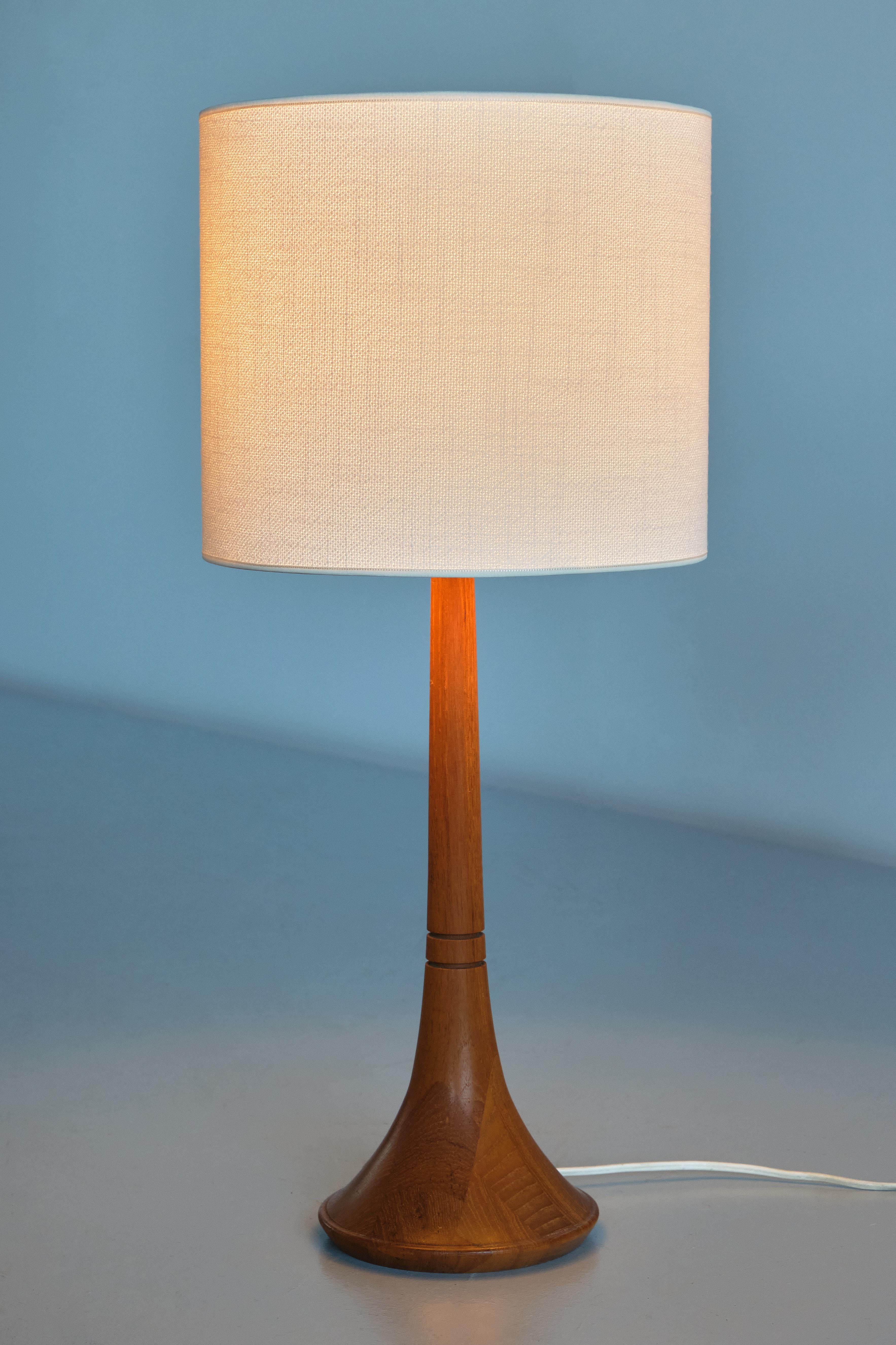 This elegant table lamp was produced by Tranås Stilarmatur AB in Sweden in the 1960s. The design is characterized by the trumpet shape of the teak wood base. The base with two carved ring details and different pieces of wood creating a striking