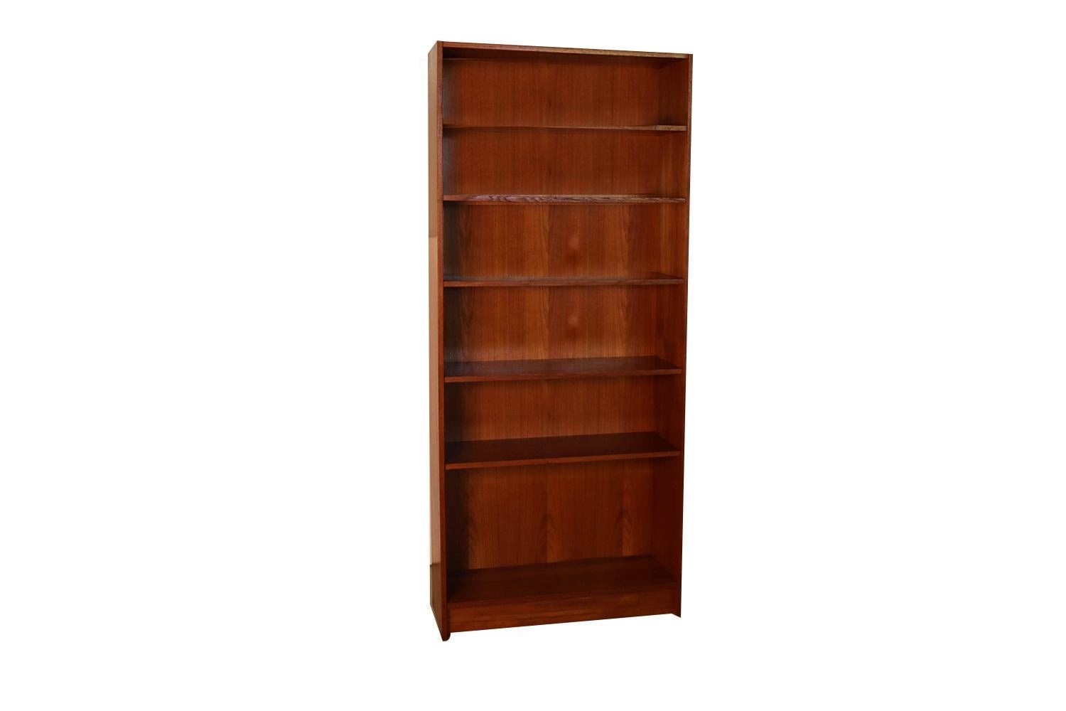 An exceptional teak tall bookcase from Denmark. Gorgeous Mid-Century Modern teak bookcase / tall bookshelf unit. Beautiful, Minimalist, clean, straight lines, features Hidden metal shelf hangers with 5 shelves: 4 adjustable, one fixed for various