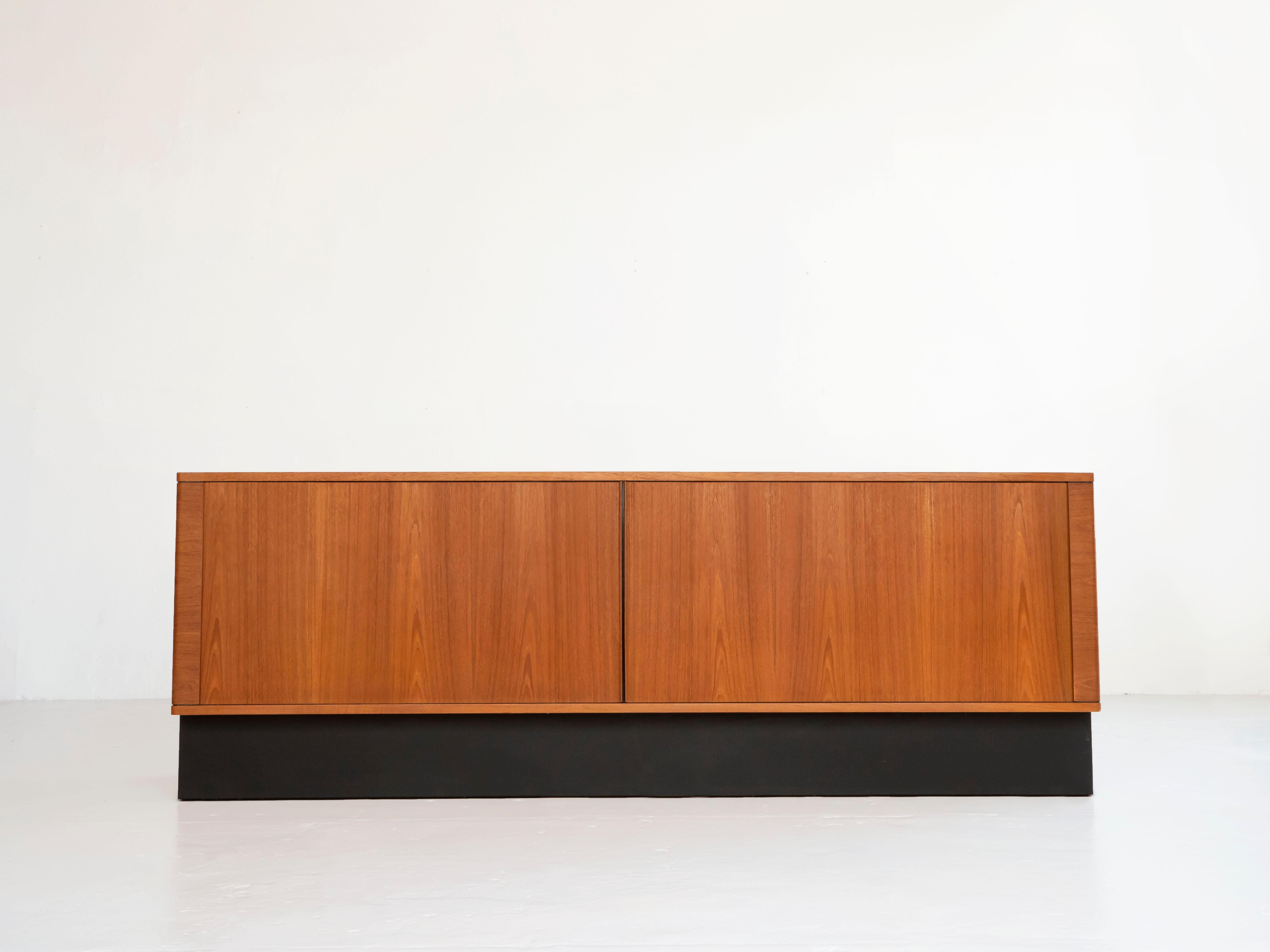 Tambour door credenza by Hornslet Mobelfabrik. Made in Denmark circa 1960’s-1970’s. It sits on a black plinth base.

Excellent condition with only minimal wear. The doors glide smooth and there is plenty of storage inside on the adjustable