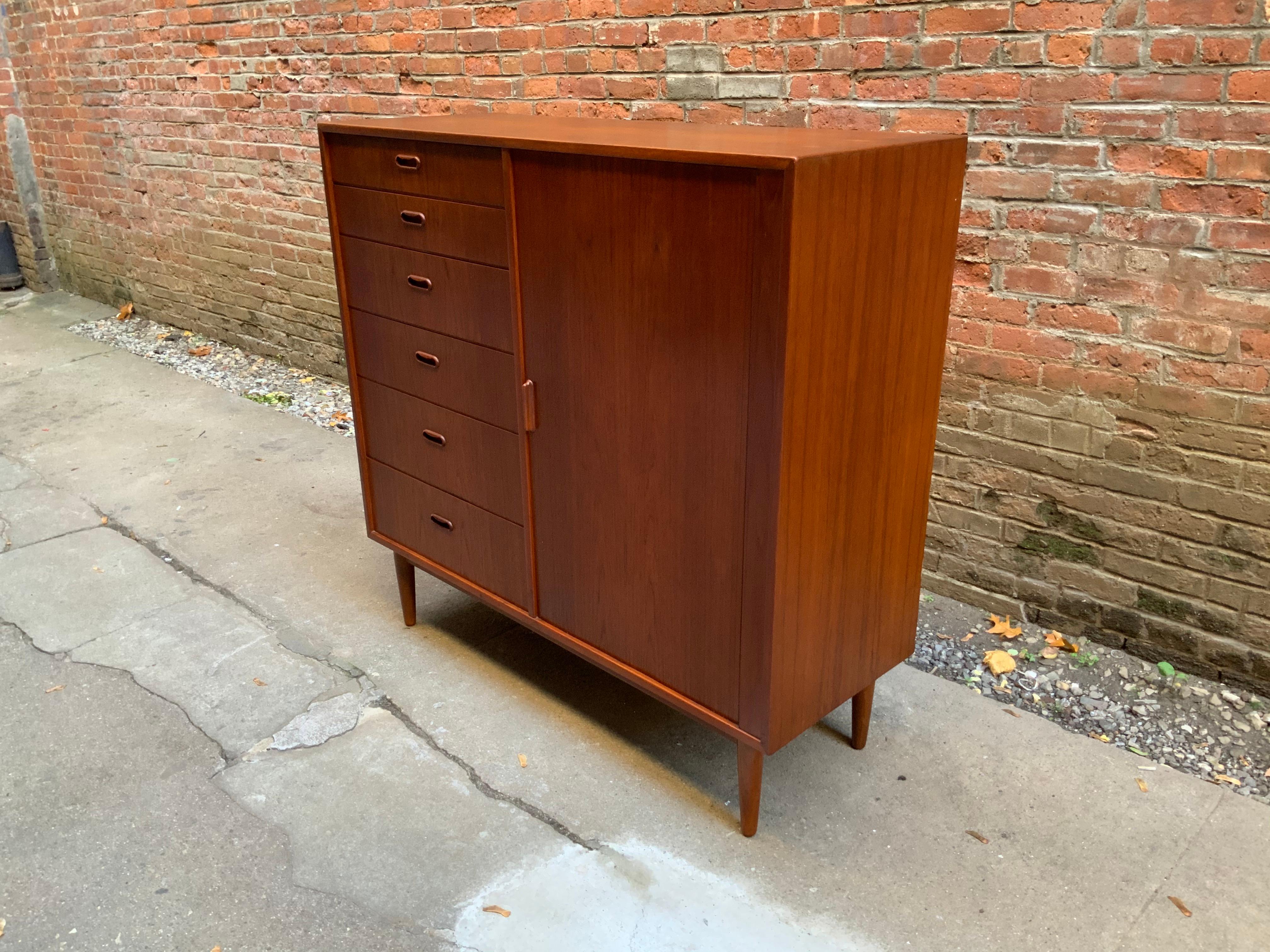 Built for maximum storage. Behind the sliding tambour door are six drawers flanked by six exterior drawers with recessed handles. Tapered legs with nicely figure teak veneers, circa 1960-1970.

Measures: 17.88
