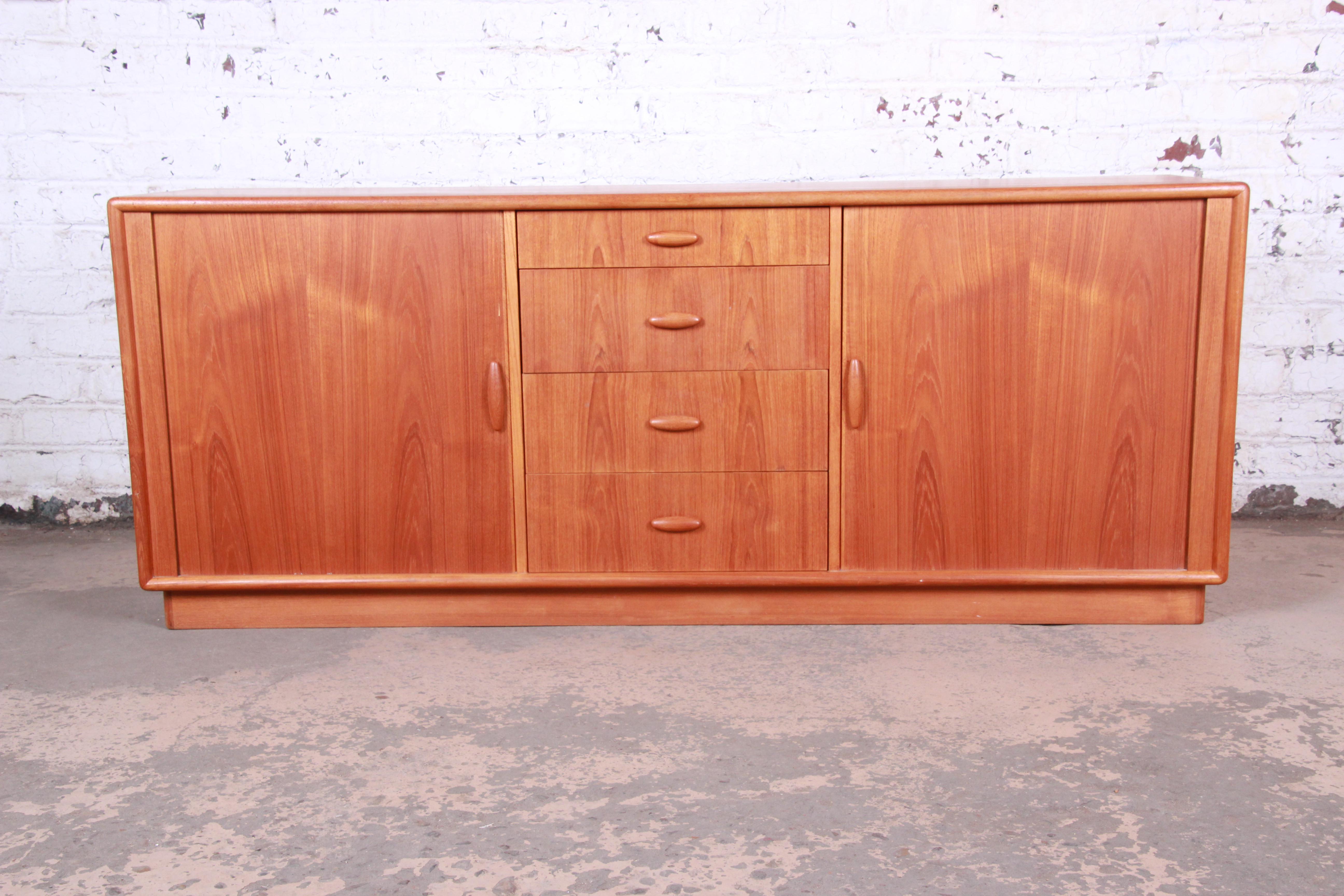 A gorgeous midcentury Danish modern teak credenza or long dresser by Dyrlund. The credenza features stunning teak wood grain and sleek midcentury Danish design. It offers ample storage, with large cabinets each with two dovetailed drawers behind