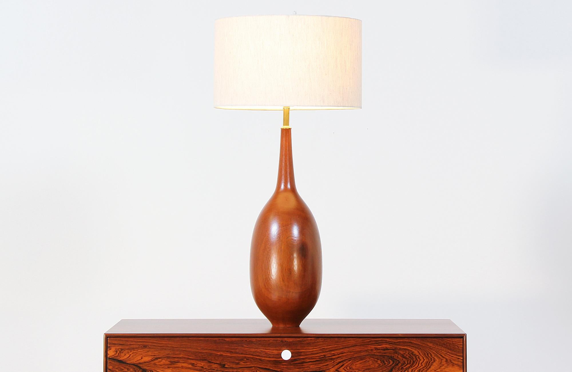 Spectacular table lamp designed and manufactured in Denmark, circa 1950s. This lamp features a teak wood turned body with organic curves in the shape of a teardrop. It is very solid and has been fully refinished, making it the perfect mid-century