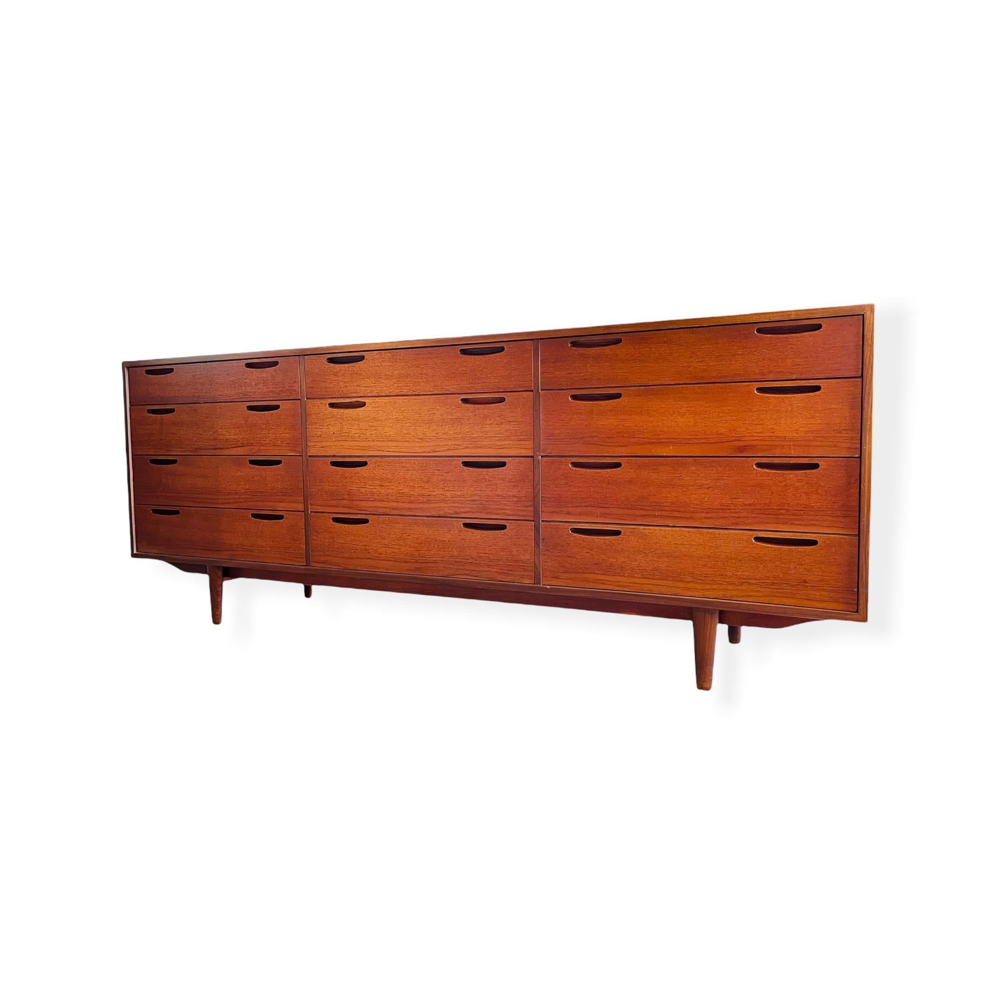 Here is a stunning mid-century Danish modern teak triple dresser by IB Kofod Larsen of Denmark. This dresser features 12 drawers with two sculpted drawer pulls on each drawer, beautiful tapered legs and a finished back. This dresser is in good
