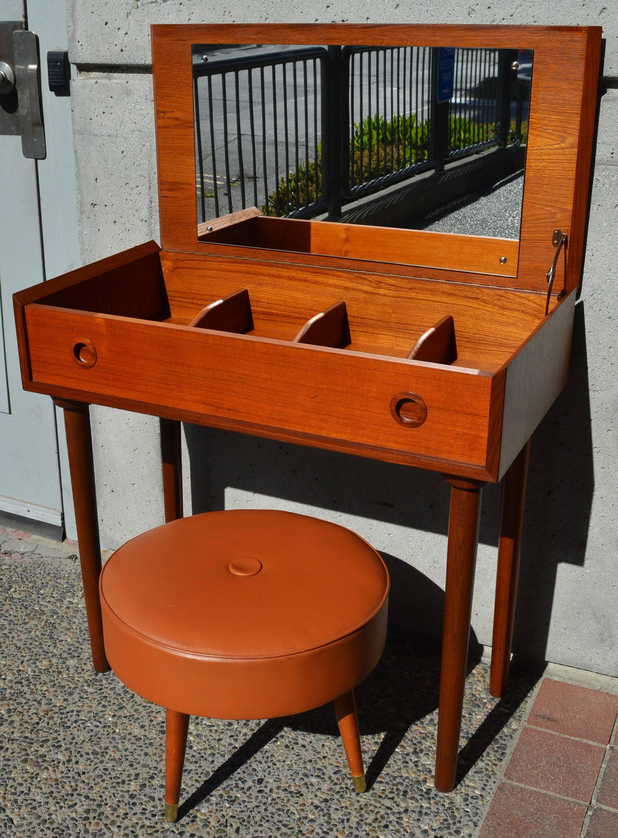 This totally sweet Danish modern teak vanity / desktop is a fabulous compact size and features lovely two-tone detailing throughout, such as the mitered edges where the top is lowered, the round faux drawer pulls, and the conical legs. Use it as a