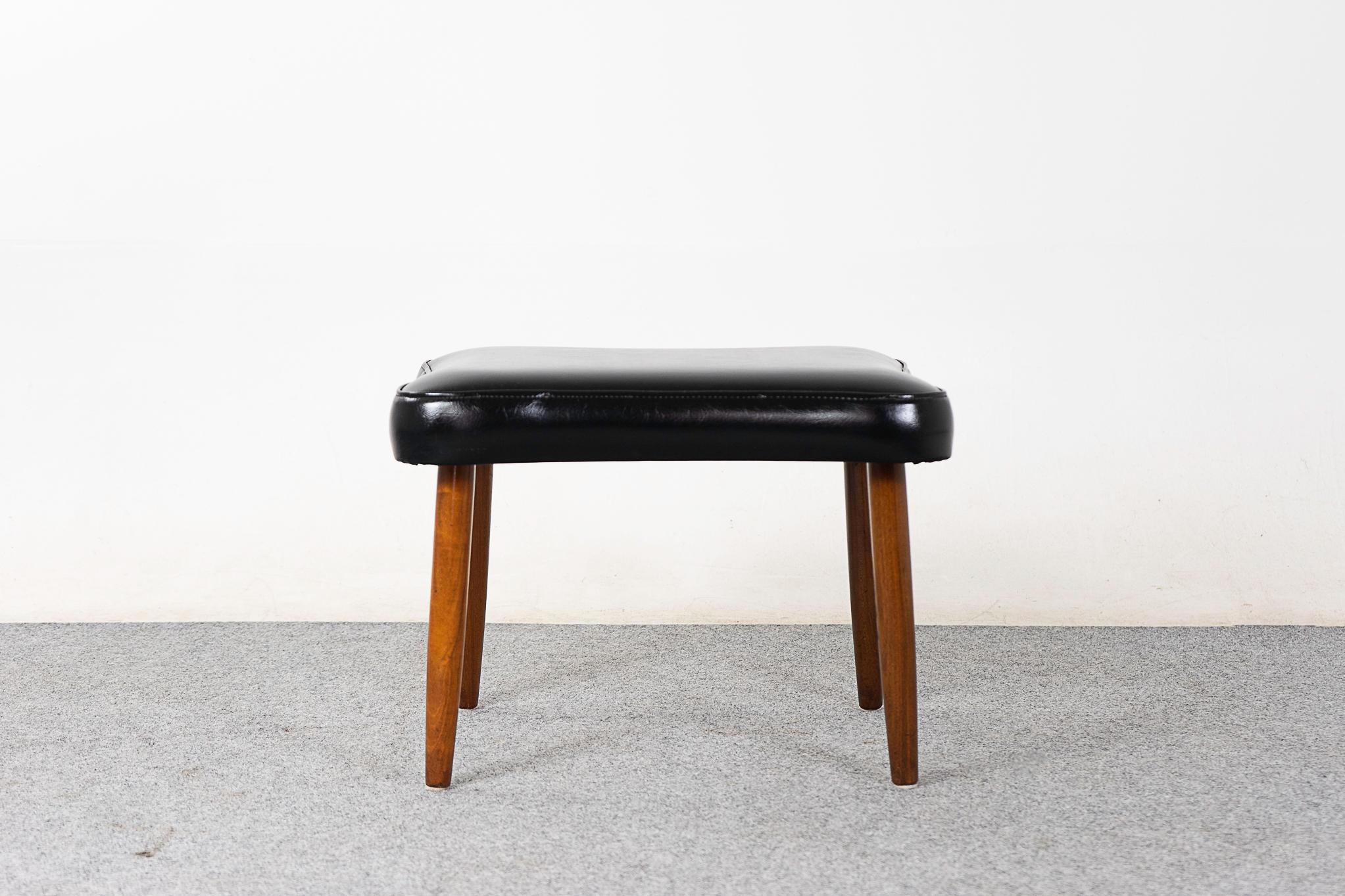Teak and vinyl footstool, circa 1960's. Compact design with original jet black upholstery with soft rounded edges. Sleek conical legs with nice patina!

Please inquire for remote and international shipping rates.