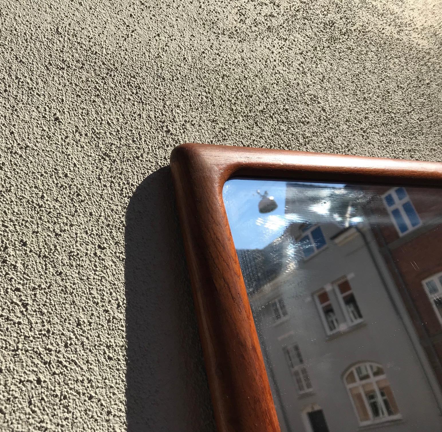 A rare full-figure wall hung mirror with solid hand sanded teak frame that has been assembled without the use of metal. It was designed by Johannes Andersen in Denmark during the 1960s. Manufactured by CFC in Silkeborg, Denmark. The maker's mark is