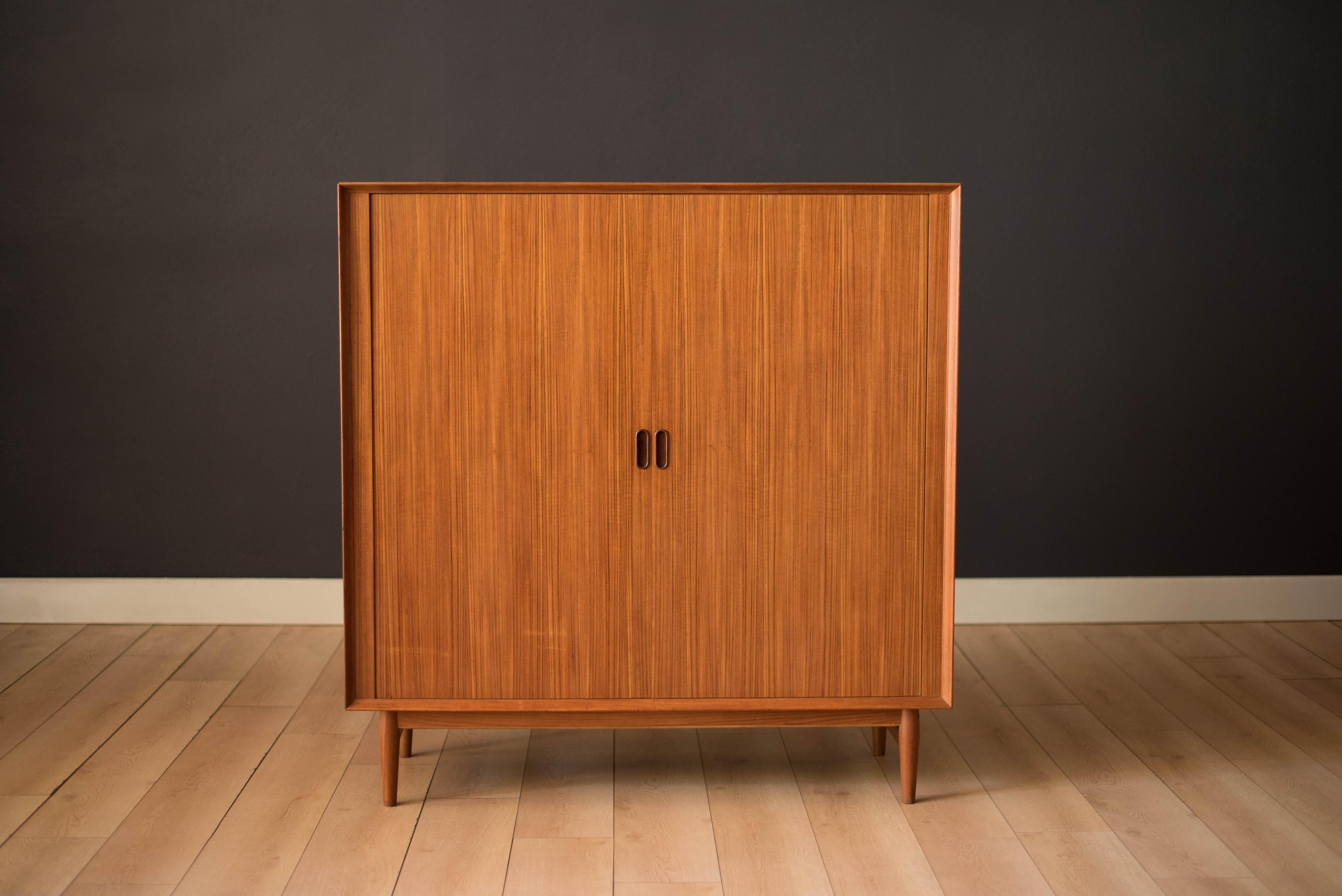 Mid-Century Modern tall wardrobe dresser chest designed by Arne Vodder for Sibast Møbler, circa 1960s, Denmark. Features a stunning and functional tambour sliding door that reveals plenty of organized storage space. Complete with eight slide out