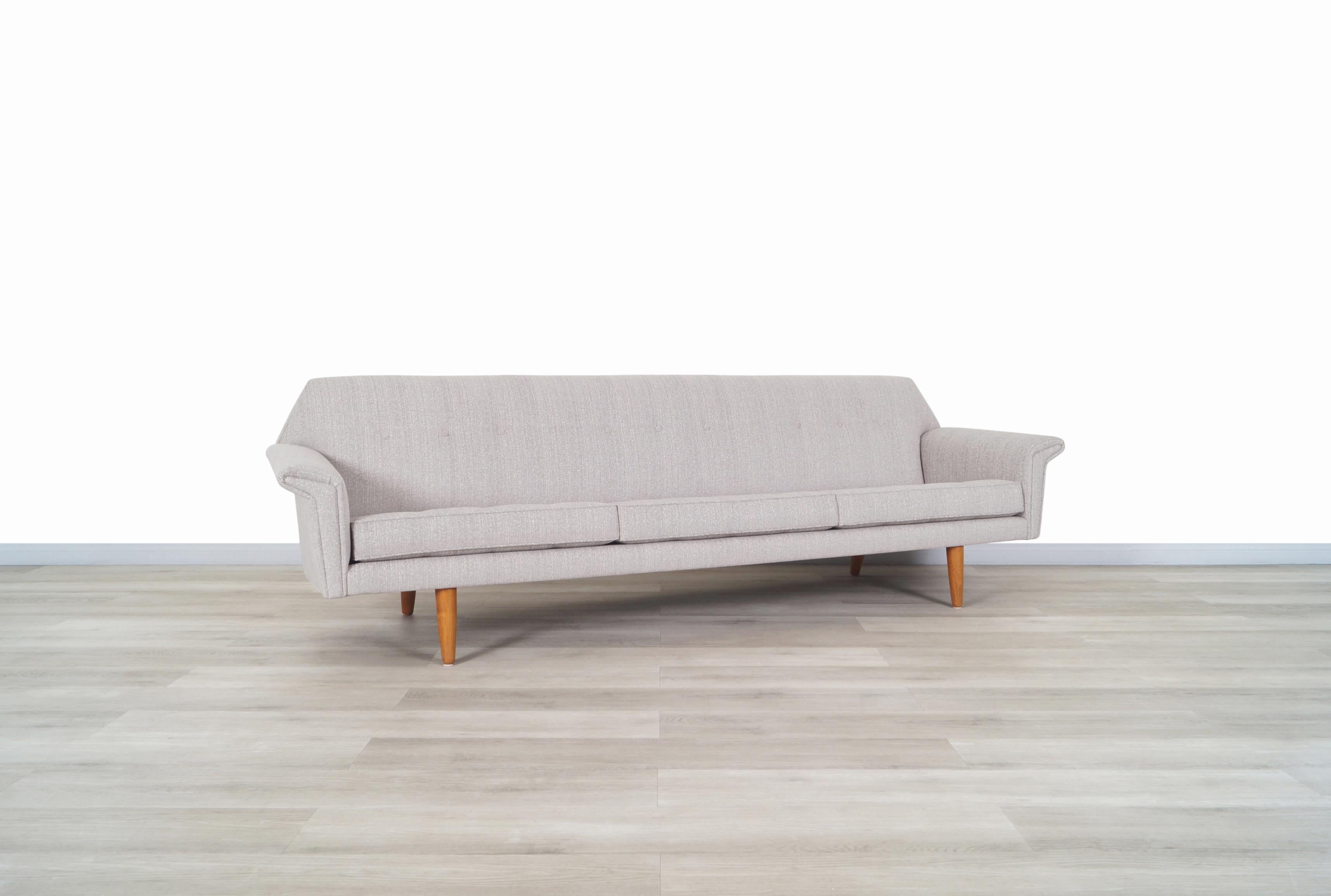 Exceptional Danish modern teak “wing” sofa designed and manufactured in Denmark, circa 1960s. The design of the armrests that are shape as wings and the geometric shape back blends perfectly with the structure of the sofa. It sits on solid teak