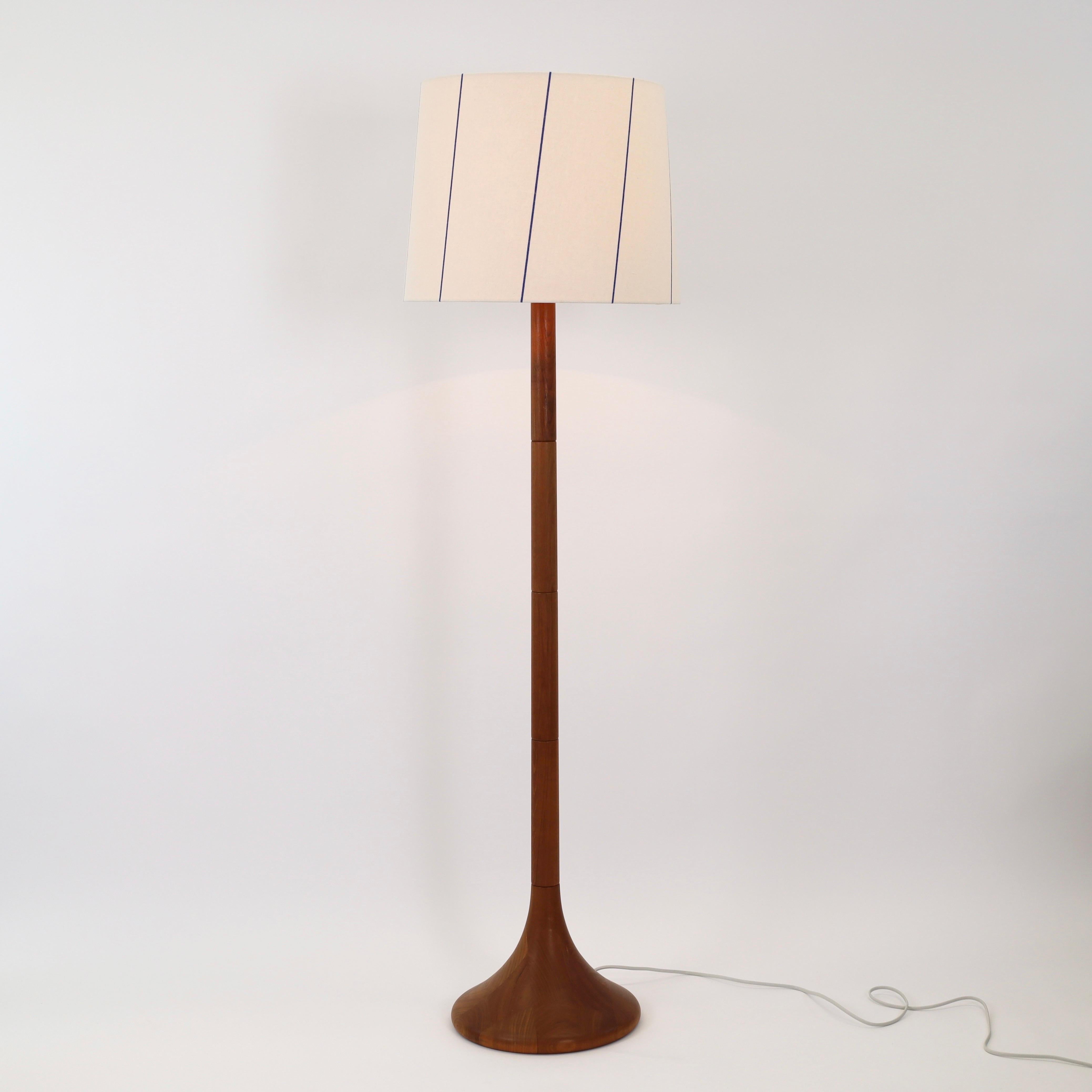 1970s Danish teak wood floor lamp in great condition accomplished a white fabric shade with blue stribes. A substantial floor lamp for a beautiful space.
 
* A teak wood floor lamp with a white fabric shade with blue stribes 
* Manufacturer: unknown