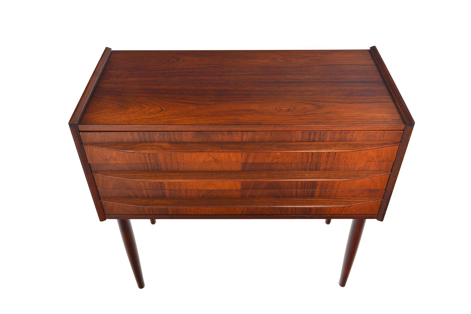 This Danish modern midcentury rosewood chest will make a wonderful addition to any modern bedroom or entryway. Three drawers with carved full profile pulls provide an excellent amount of storage. Case sits upon spindle legs. In excellent original