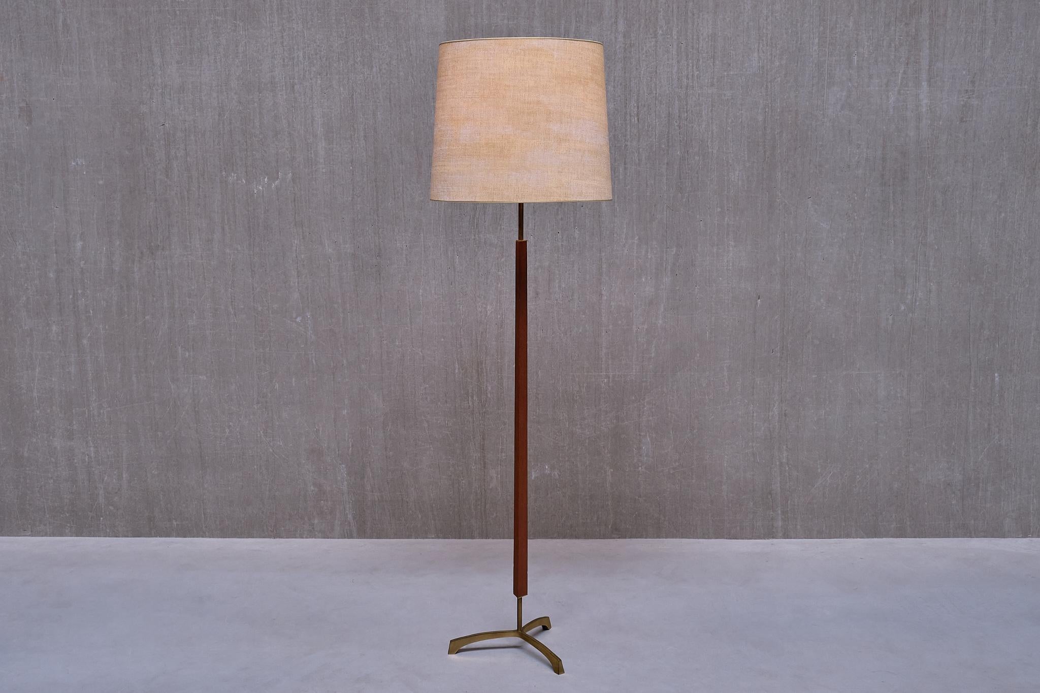 This rare floor lamp was produced in Denmark in the late 1950s. 

The lamp features a distinctive slightly raised, three legged base crafted from solid brass. The central stem in teak wood is made in a triangular shape, adding to the architectural
