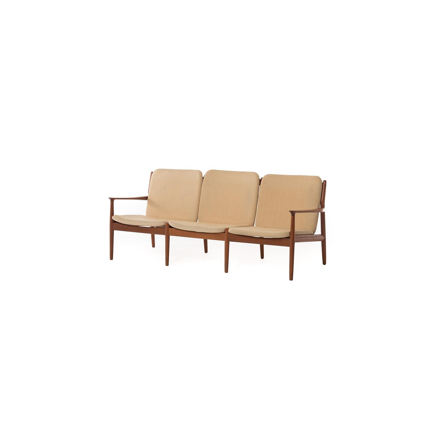 This elegant three-seat sofa rests atop a teak frame featuring sculptural arms. The slatted back makes it attractive from all angles.