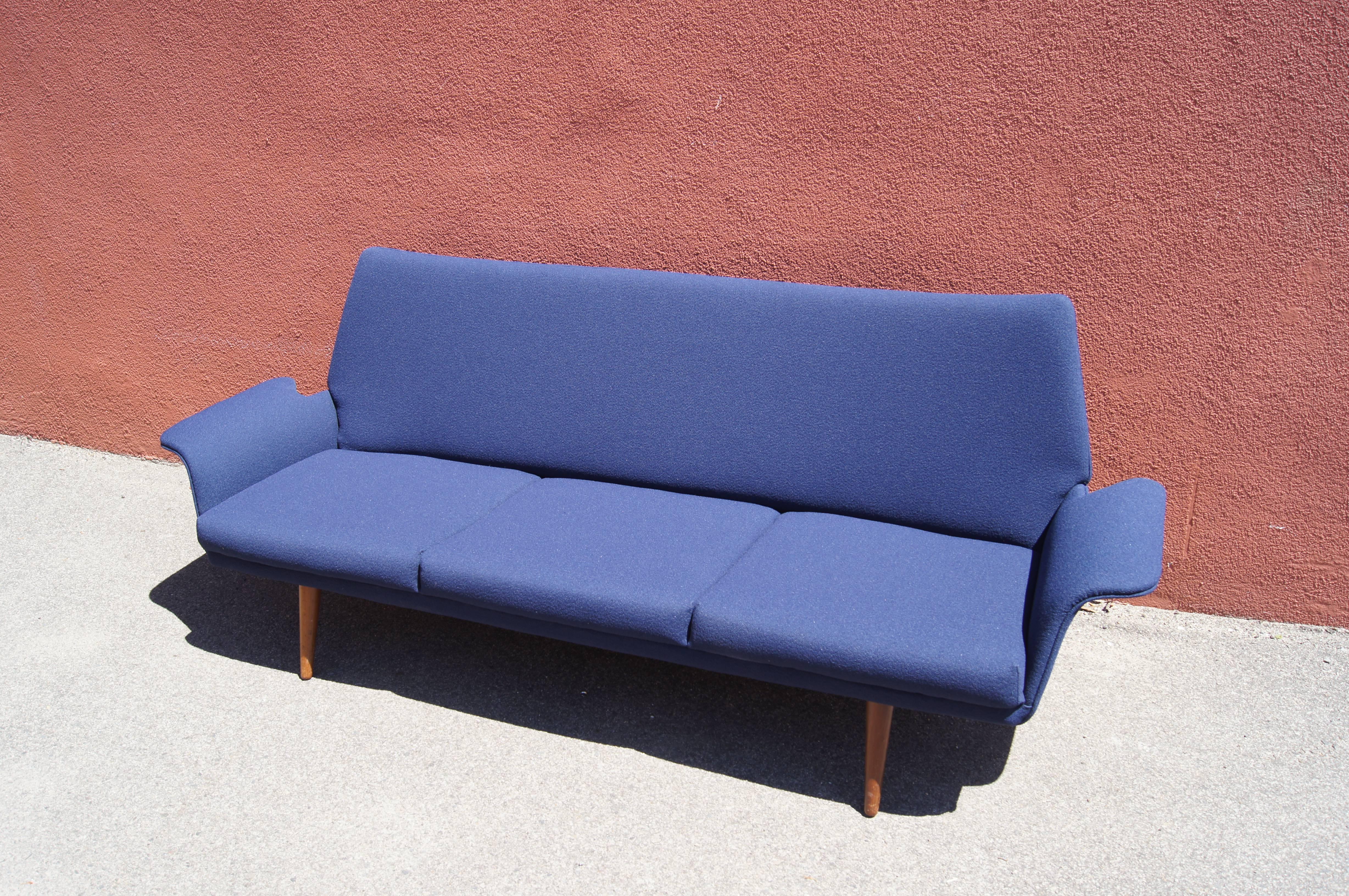 A wonderful example of Danish modern design, this three-seat sofa rests lightly on splayed legs. Its playfully curved frame has been newly upholstered in Knoll's Swing textile in Banker Blue.