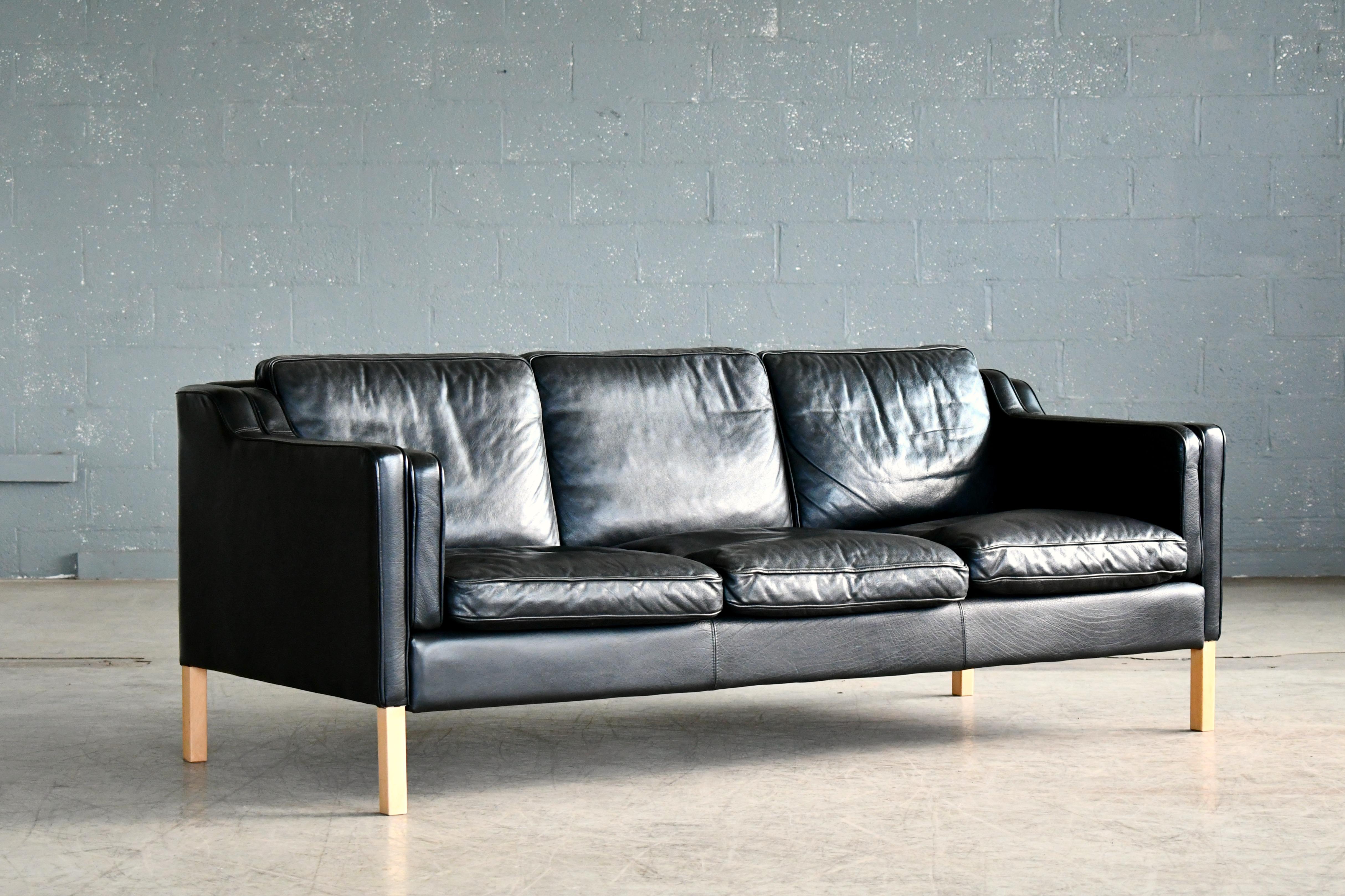 Very elegant and comfortable Classic Børge Mogensen style sofa model 2213 in supple black leather by Stouby Polsterfabrik of Denmark. High quality top grain leather over a beech wood frame and legs. Cushions are top filled with down. Nice worn-in