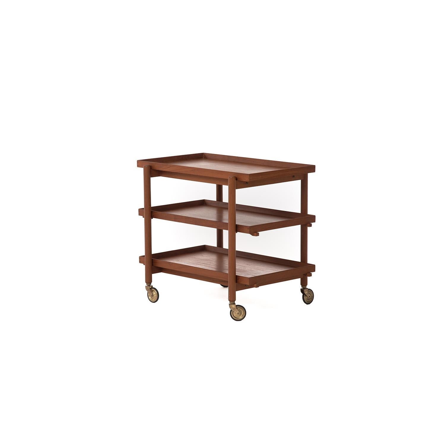 This Danish modern serving or bar cart by Poul Hundevad is made from old growth teak and finished traditionally with oil. The three-tiered design allows for multiple storage options, the middle and bottom shelves can double as serving trays. The