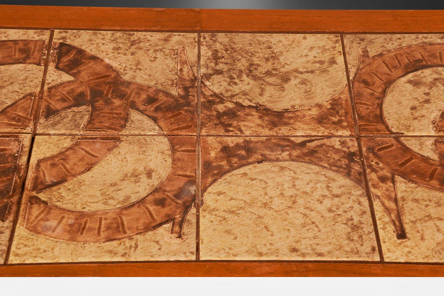 A beautiful Danish Modern teak tile top, rectangular coffee table is attributed to Mobelfabrikken Toften of Denmark during the 1970’s. The table top features 10 ceramic tiles framed in teak over four square solid teak legs. The tiles are adorned